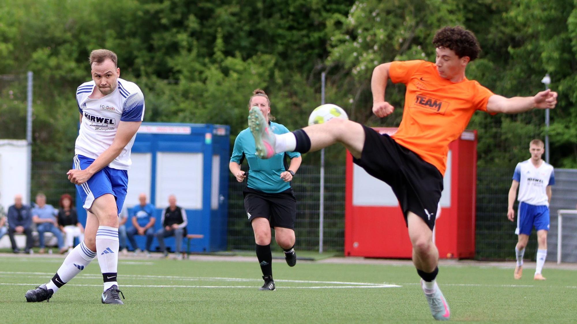 Ein Fußballer wehrt mit dem ausgestreckten Bein einen Schuss ab.