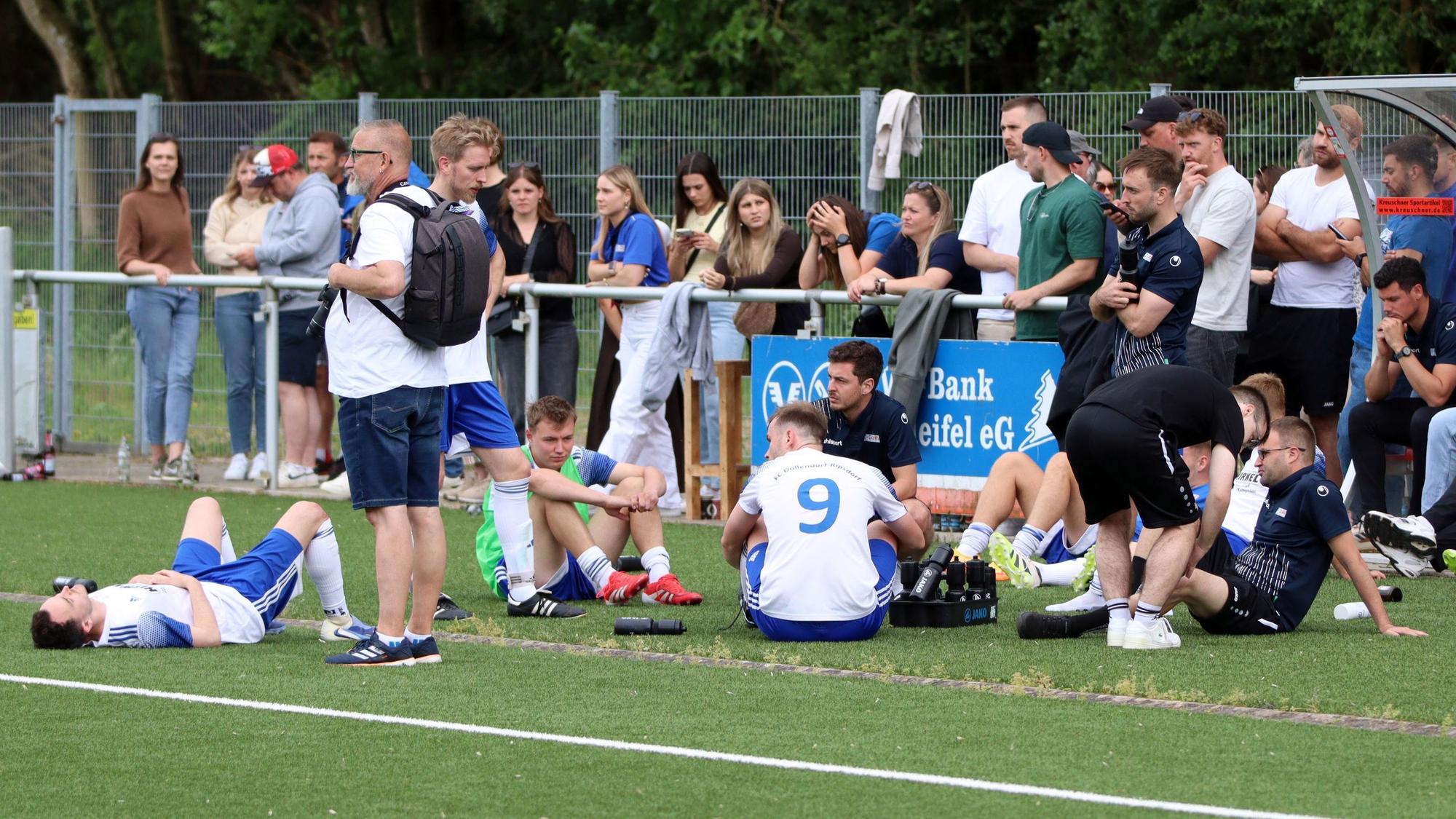 Spieler des FC Dollendorf-Ripsdorf liegen und sitzen enttäuscht auf dem Kunstrasen.