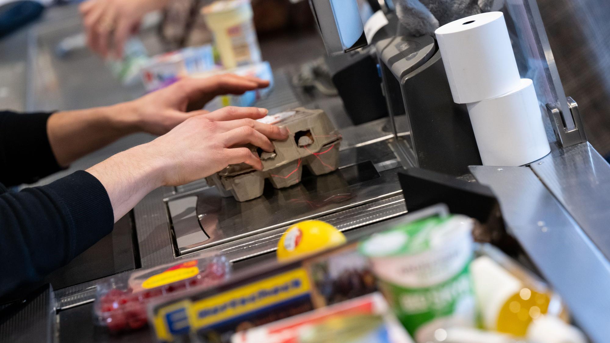 Ein Kassierer scannt in einem Supermarkt an der Kasse die Produkte.