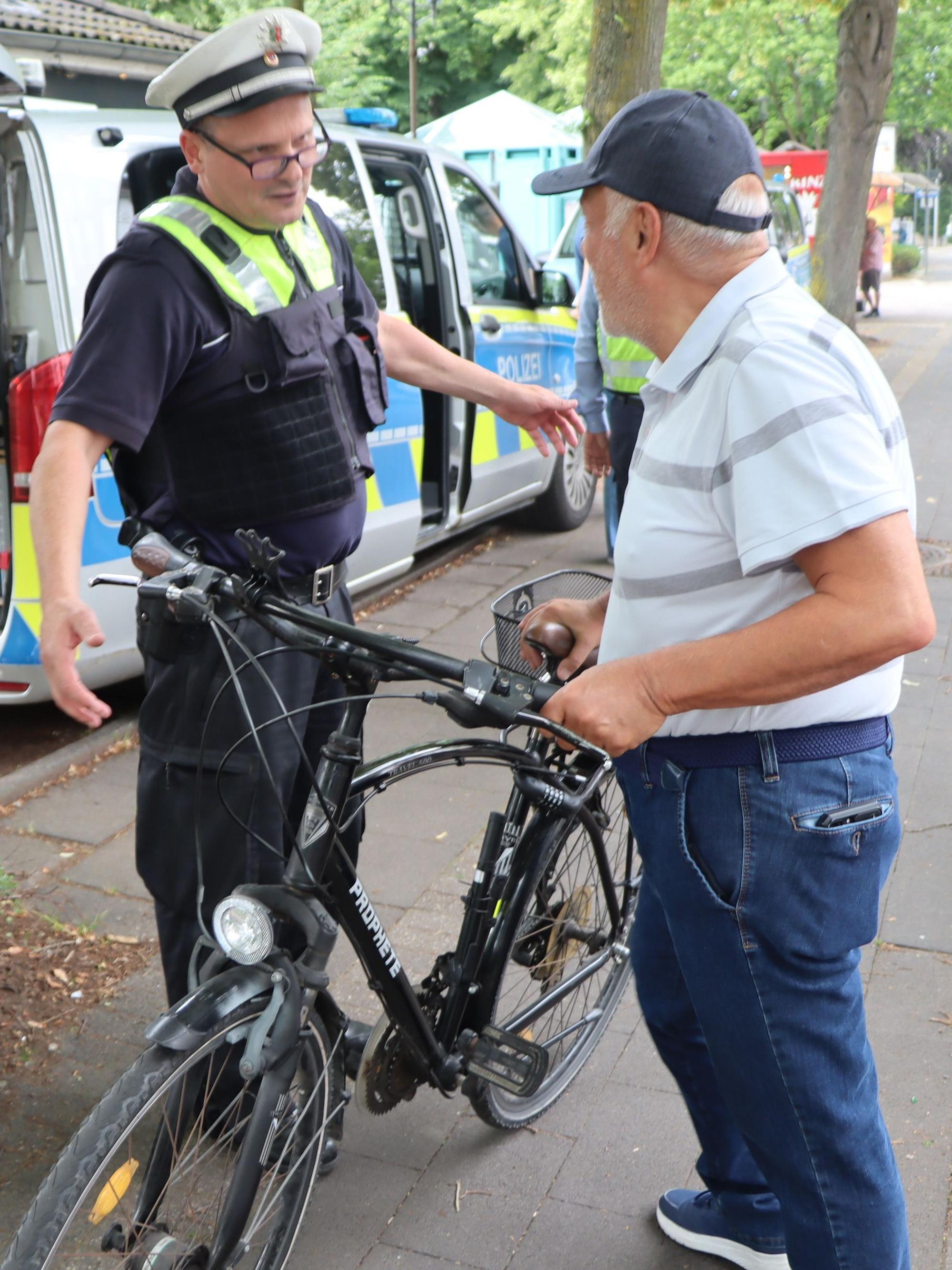 Das Bild zeigt einen Polizeibeamten und einen Fahrradfahrer.
