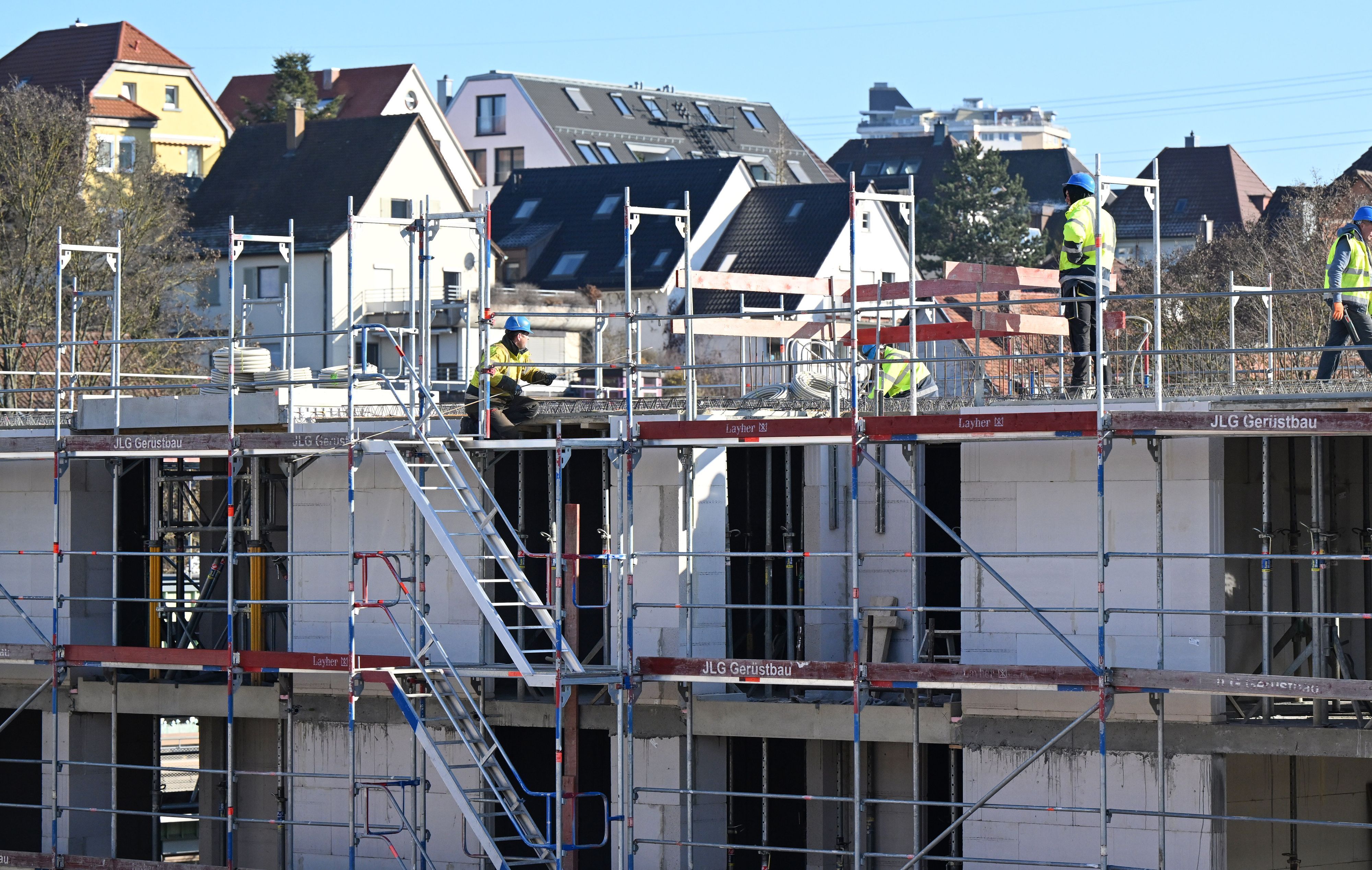 Auf einer Baustelle für Wohnungen und Sozialwohnungen arbeiten Bauarbeiter am Rohbau.