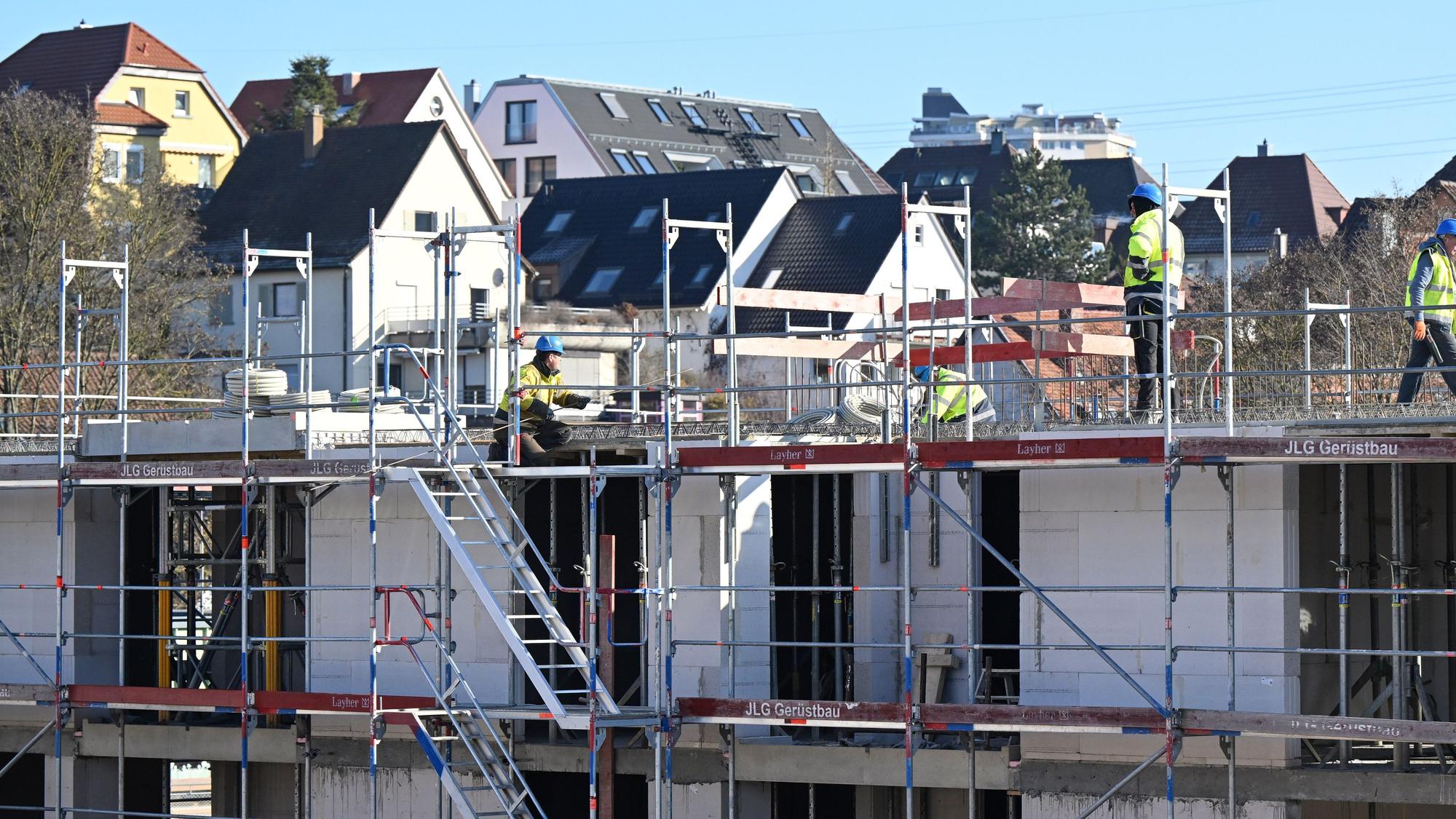 Auf einer Baustelle für Wohnungen und Sozialwohnungen arbeiten Bauarbeiter am Rohbau.