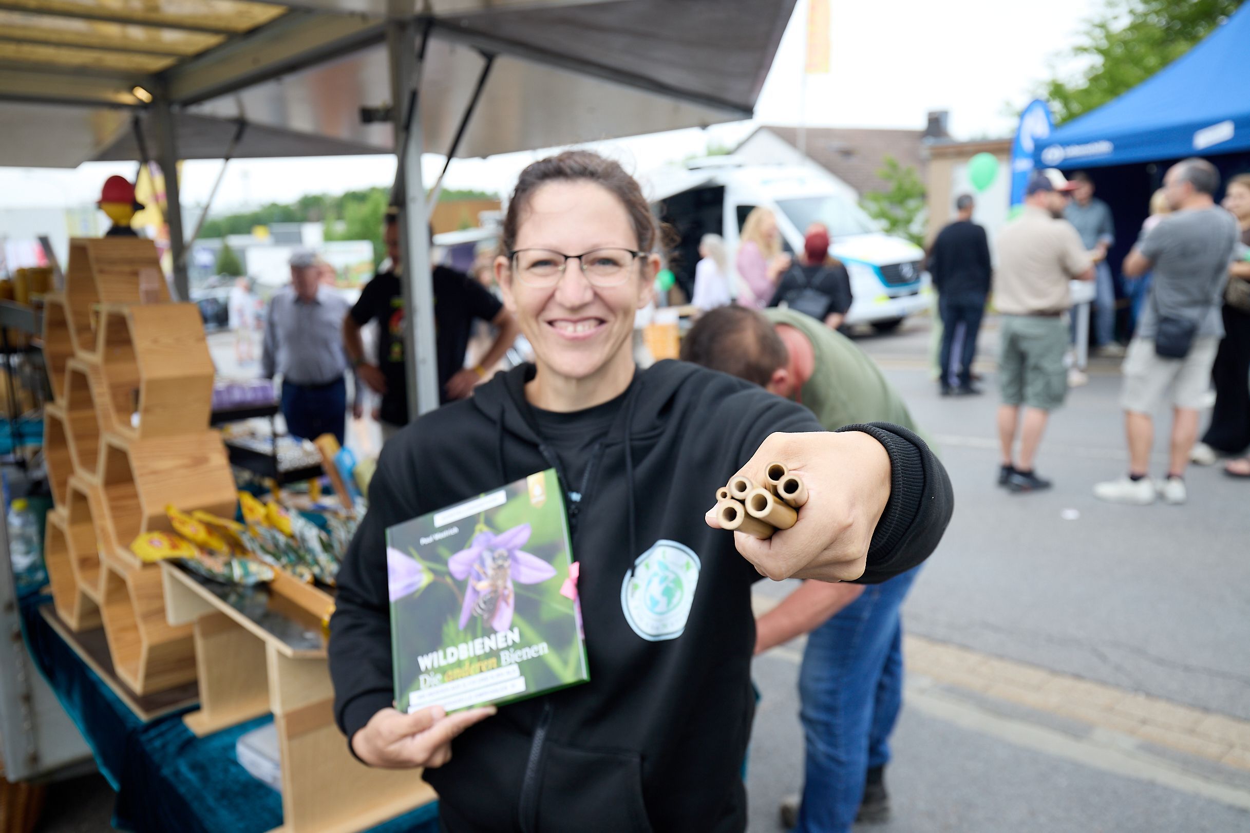 Sonja Walter zeigt Bambusröhren vor ihrem Stand mit Imkereiprodukten.