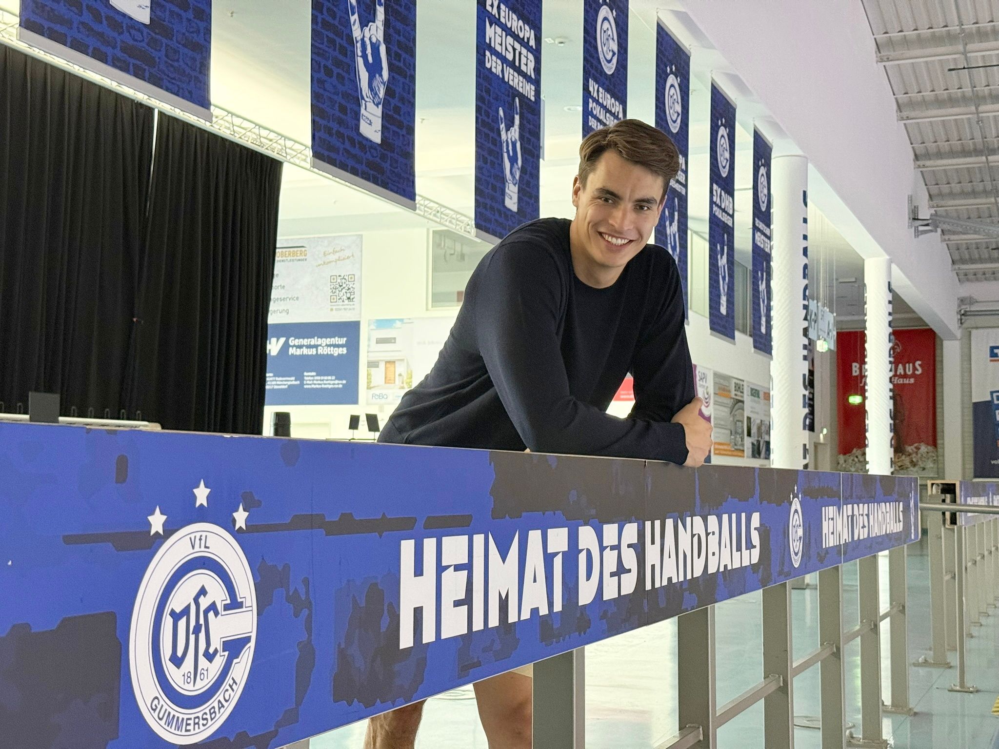 Zu sehen ist ein Handballer, der an einer Bande lehnt.