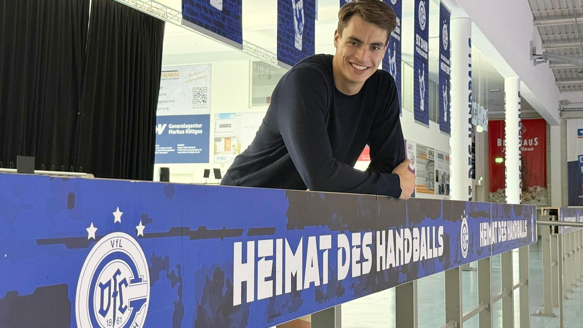Zu sehen ist ein Handballer, der an einer Bande lehnt.