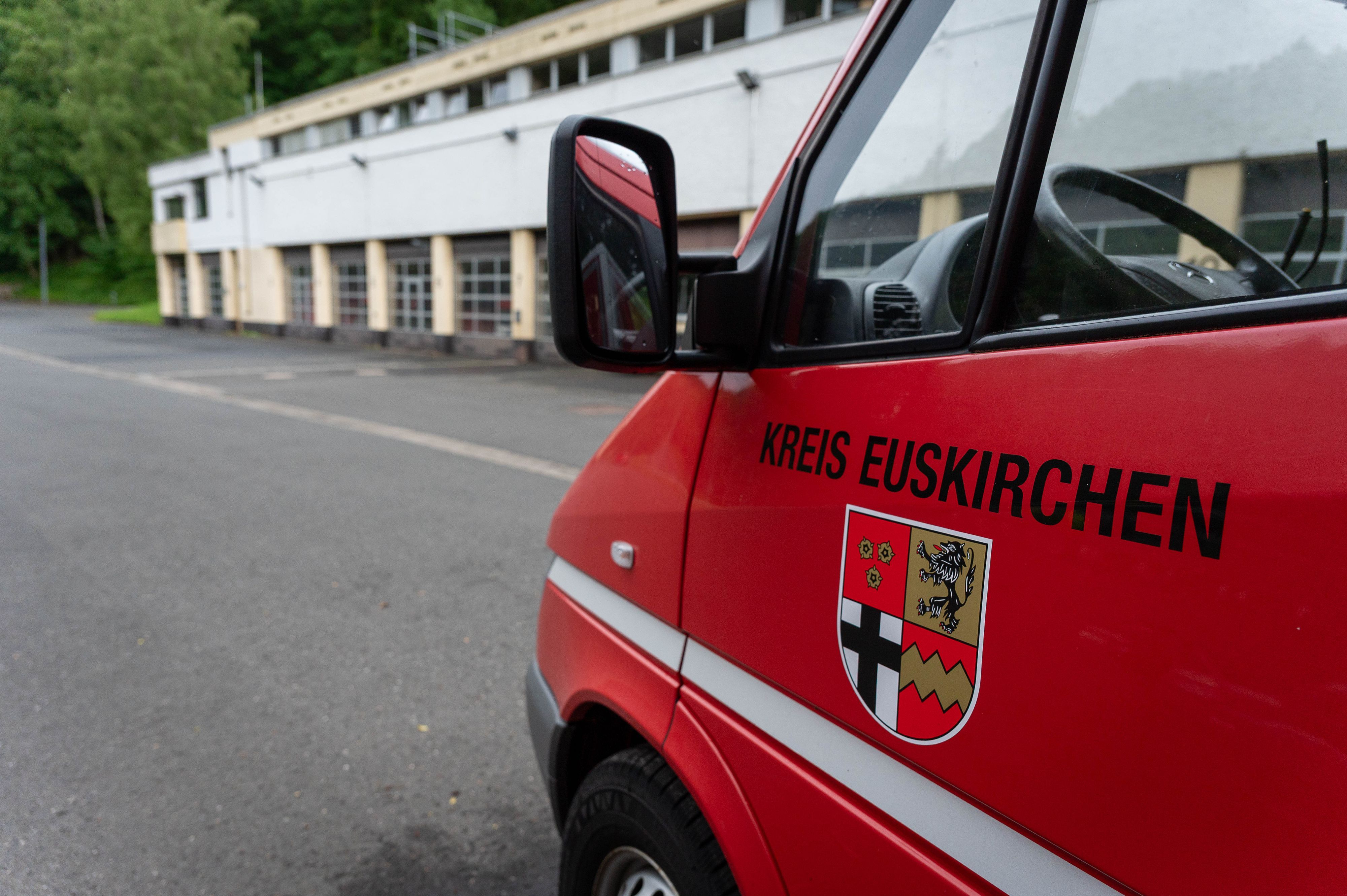 Im Hintergrund ist das Brandschutzzentrum des Kreises Euskirchen in Schleiden zu sehen, im Vordergrund ein Feuerwehrfahrzeug mit dem Kreis-Wappen und der Aufschrift „Kreis Euskirchen“.