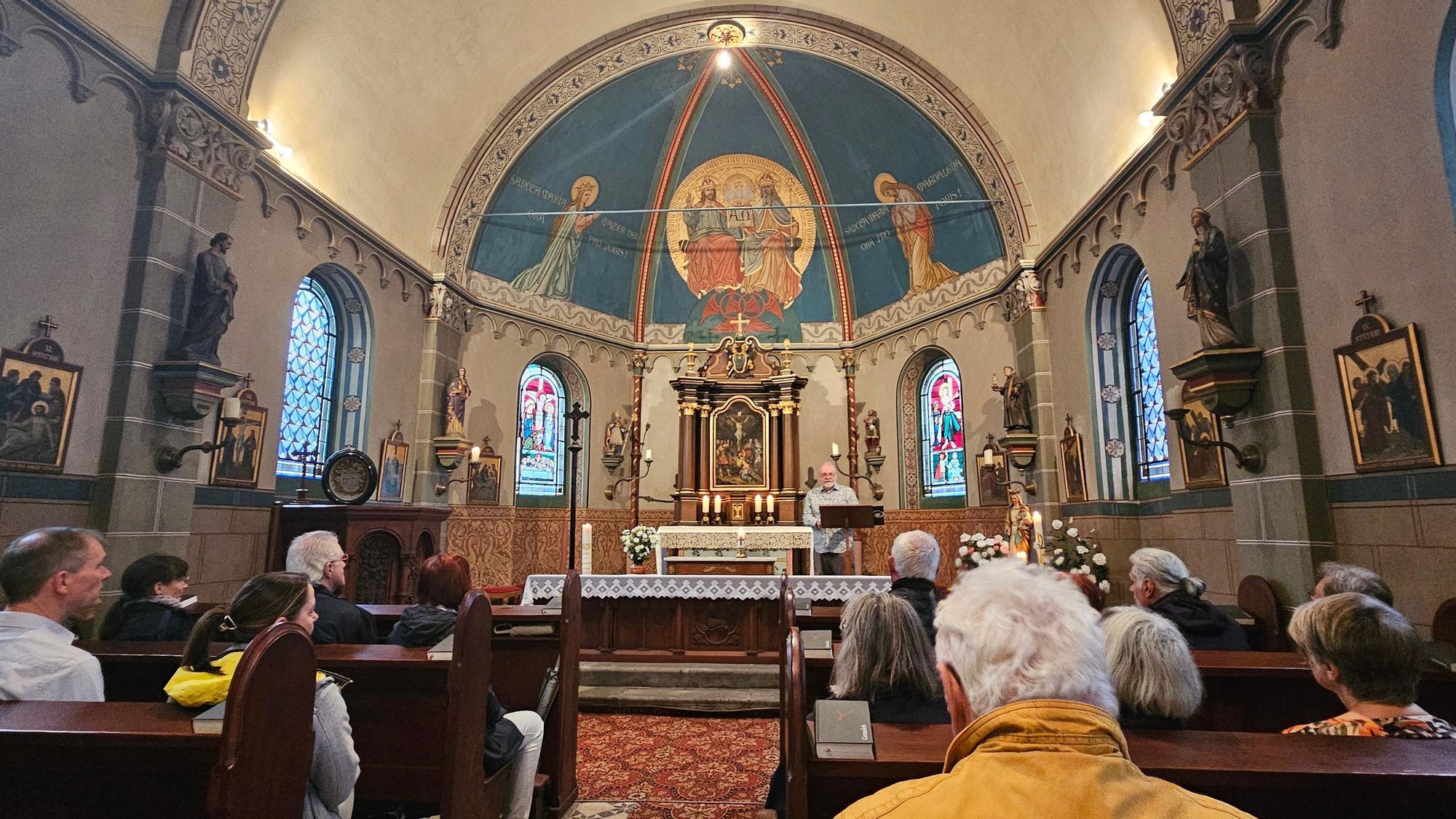 Zu sehen sind Besucherinnen und Besucher in einer Kapelle.