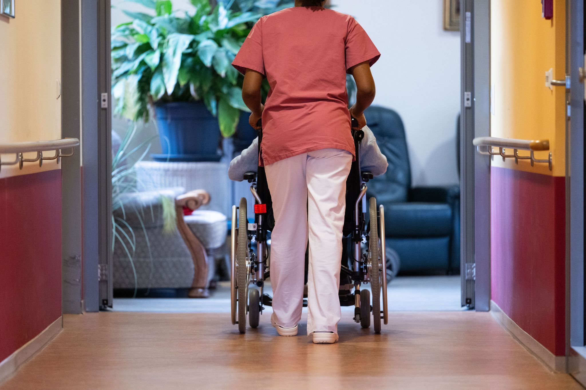 Eine Pflegekraft schiebt einen Pflegebedürftigen im Rollstuhl