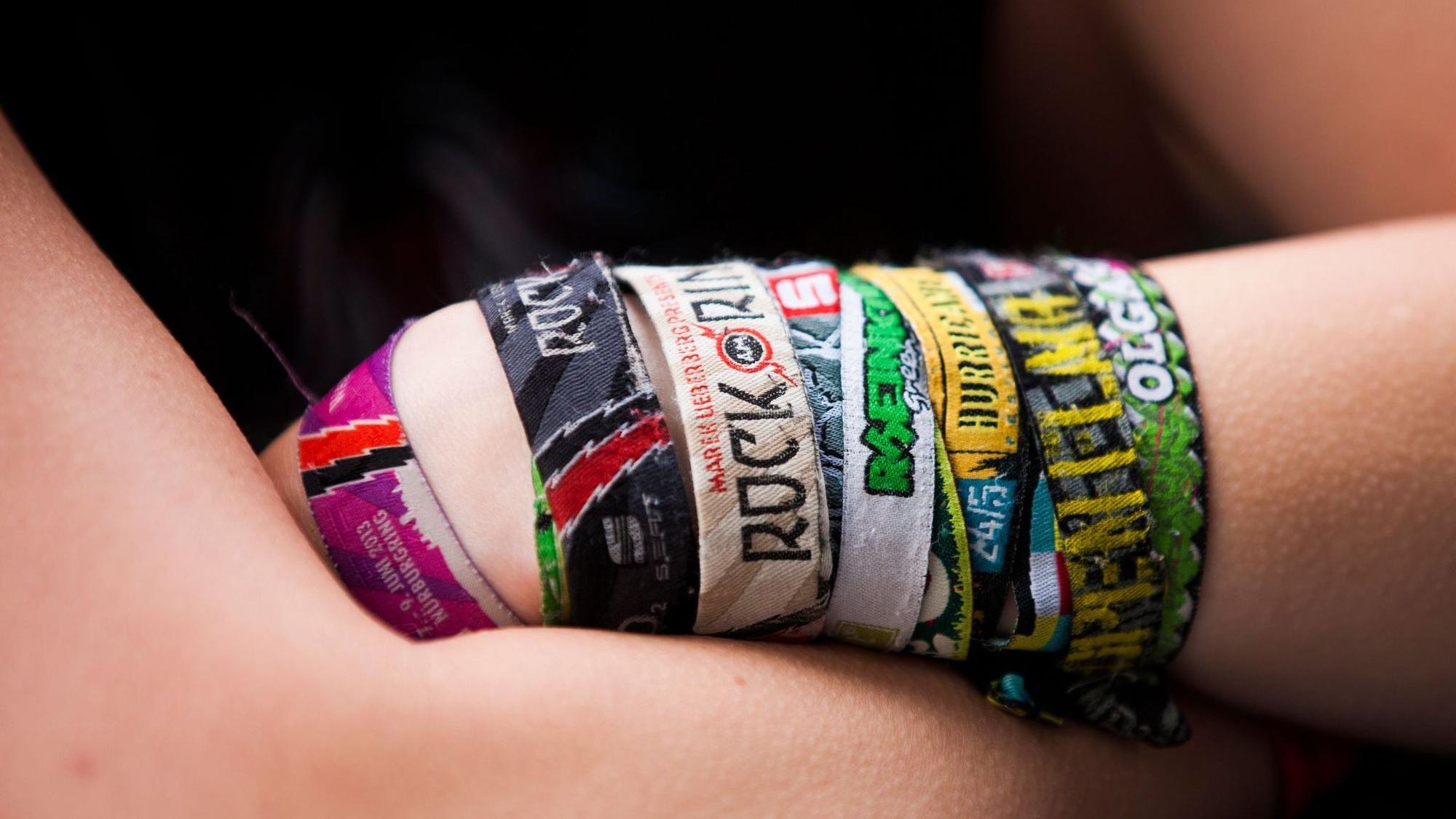 Ein Festival-Fan mit verschiedenen Bändchen verschränkt die Arme