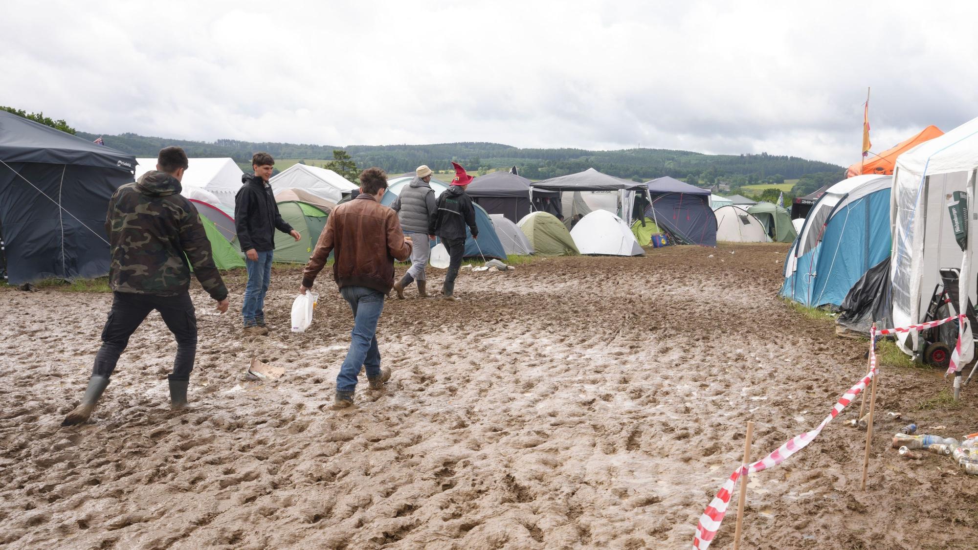 Rock am Ring: Camper gehen durch den Schlamm.