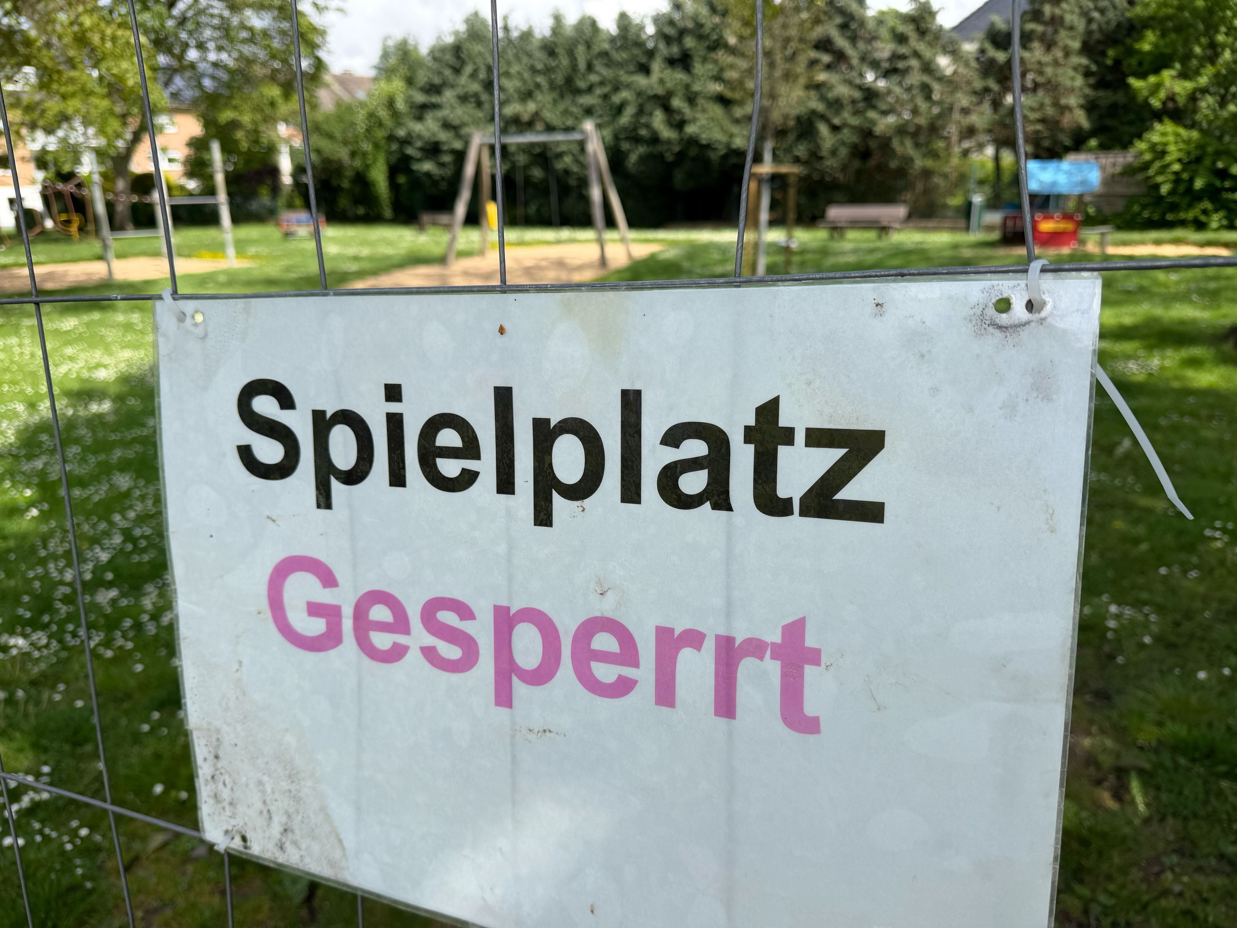 Ein Schild mit der Aufschrift „Spielplatz gesperrt“ hängt an einem Bauzaun.