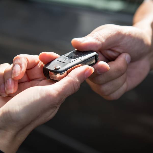 Eine Frau übergibt einen Autoschlüssel