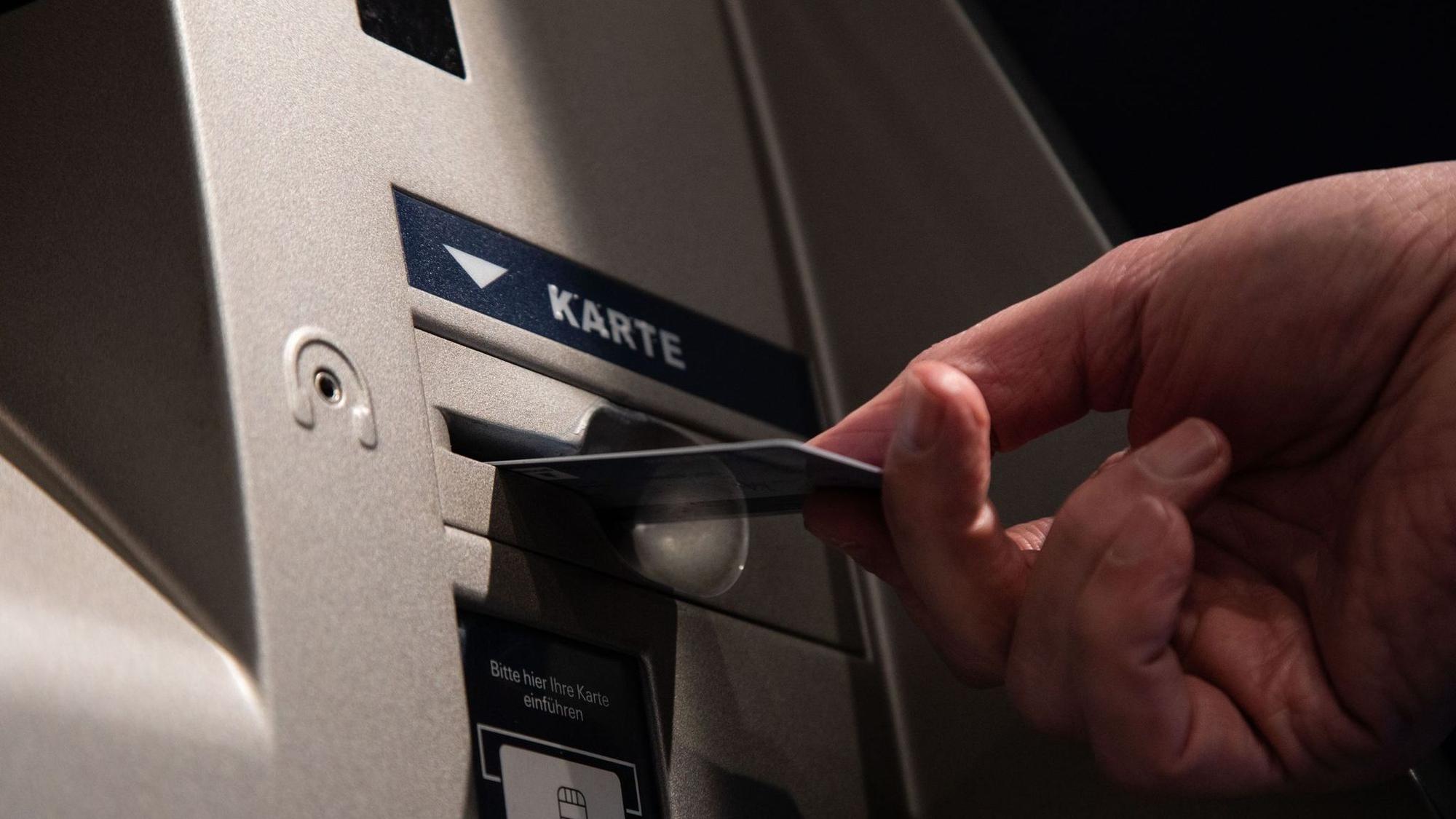 Ein Mann mit Karte an einen Bankautomaten