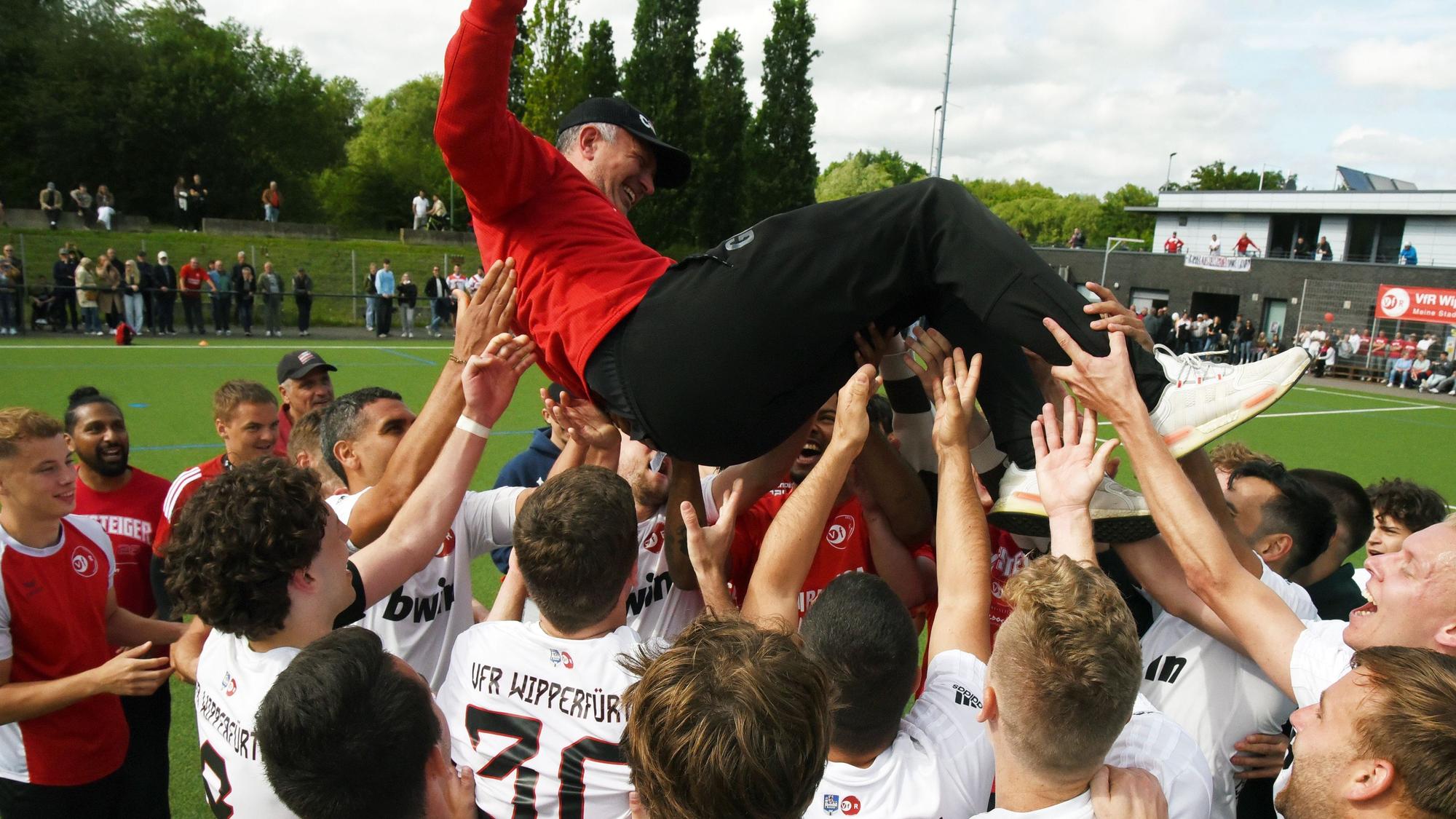 Fußballspieler werfen ihren Trainer in die Luft und feiern ihn.