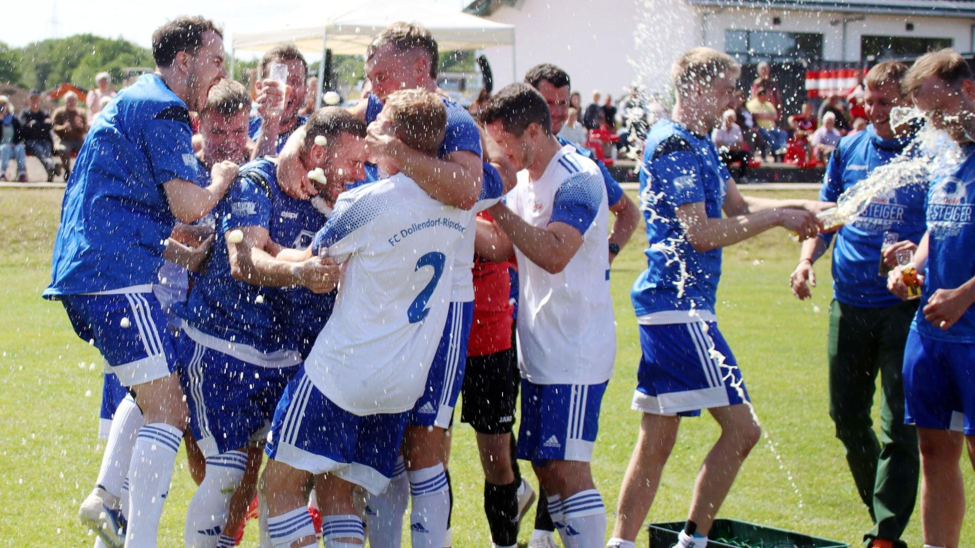 Fußballspieler jubeln, das Bier spritzt sie nass.