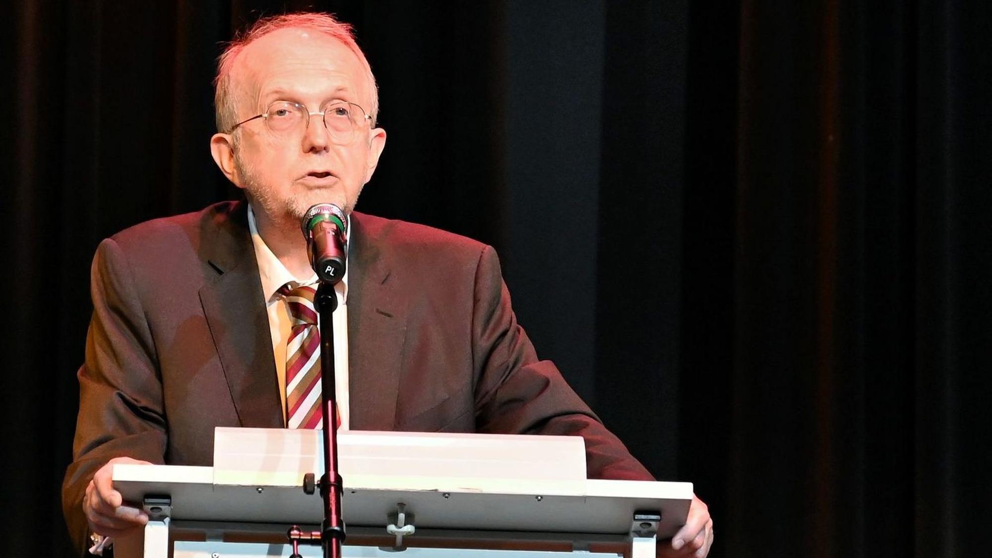 Schulleiter Michael Szczekalla steht an einem Pult und spricht in ein Mikrofon.