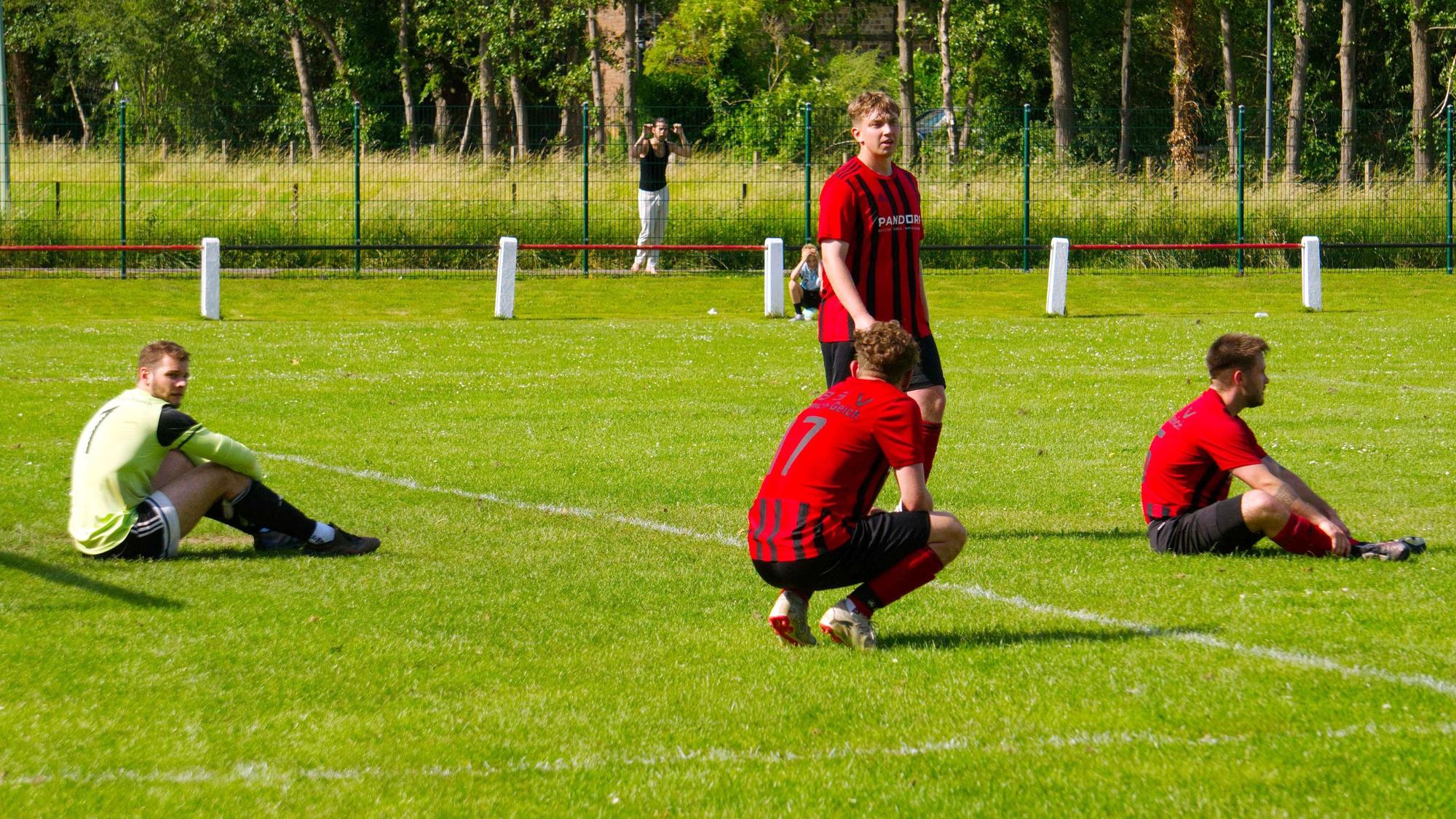 Spieler der TB-SV Füssenich-Geich sitzen traurig auf dem Spielfeld.