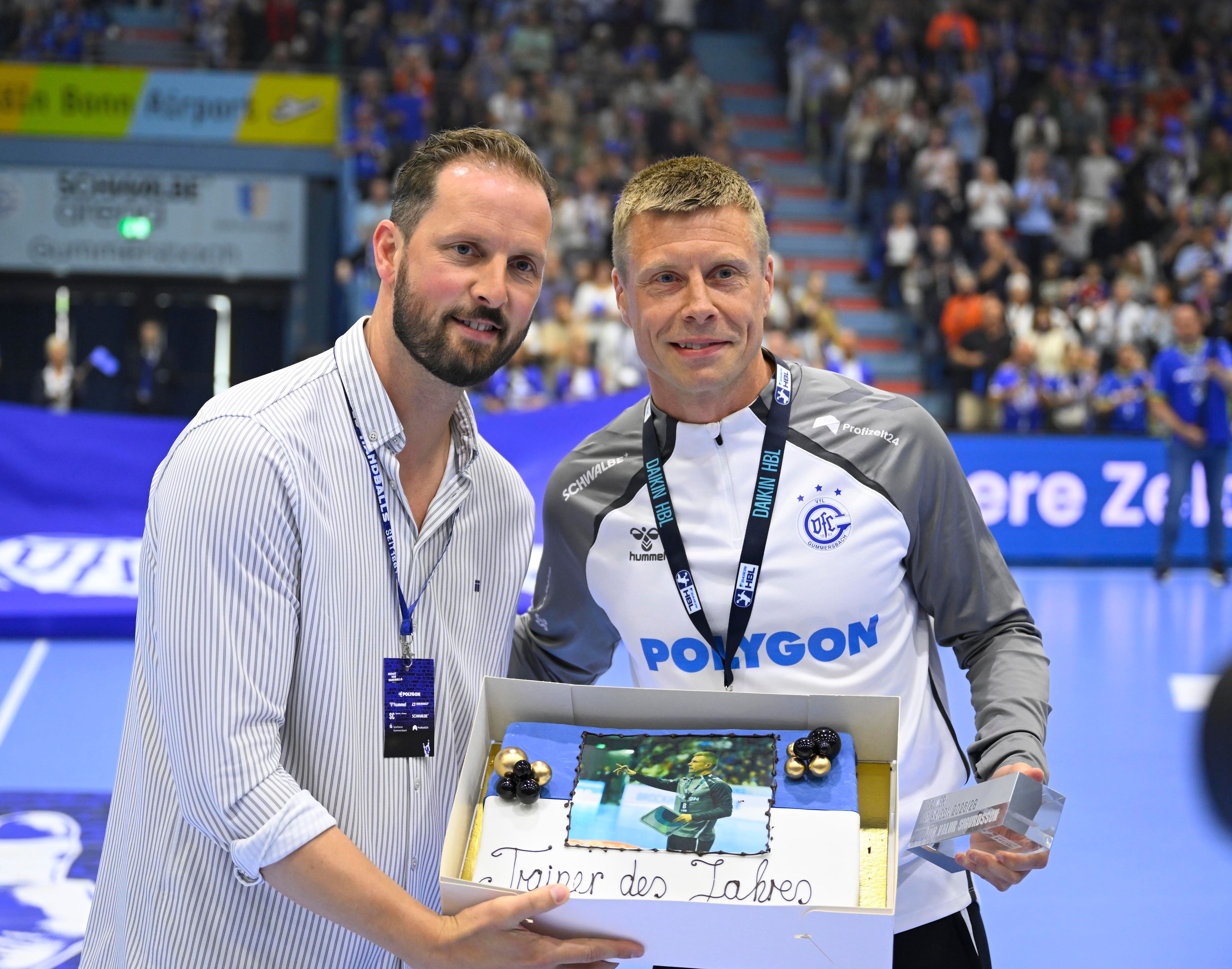 Schindler überreicht Sigurdsson einen Kuchen.