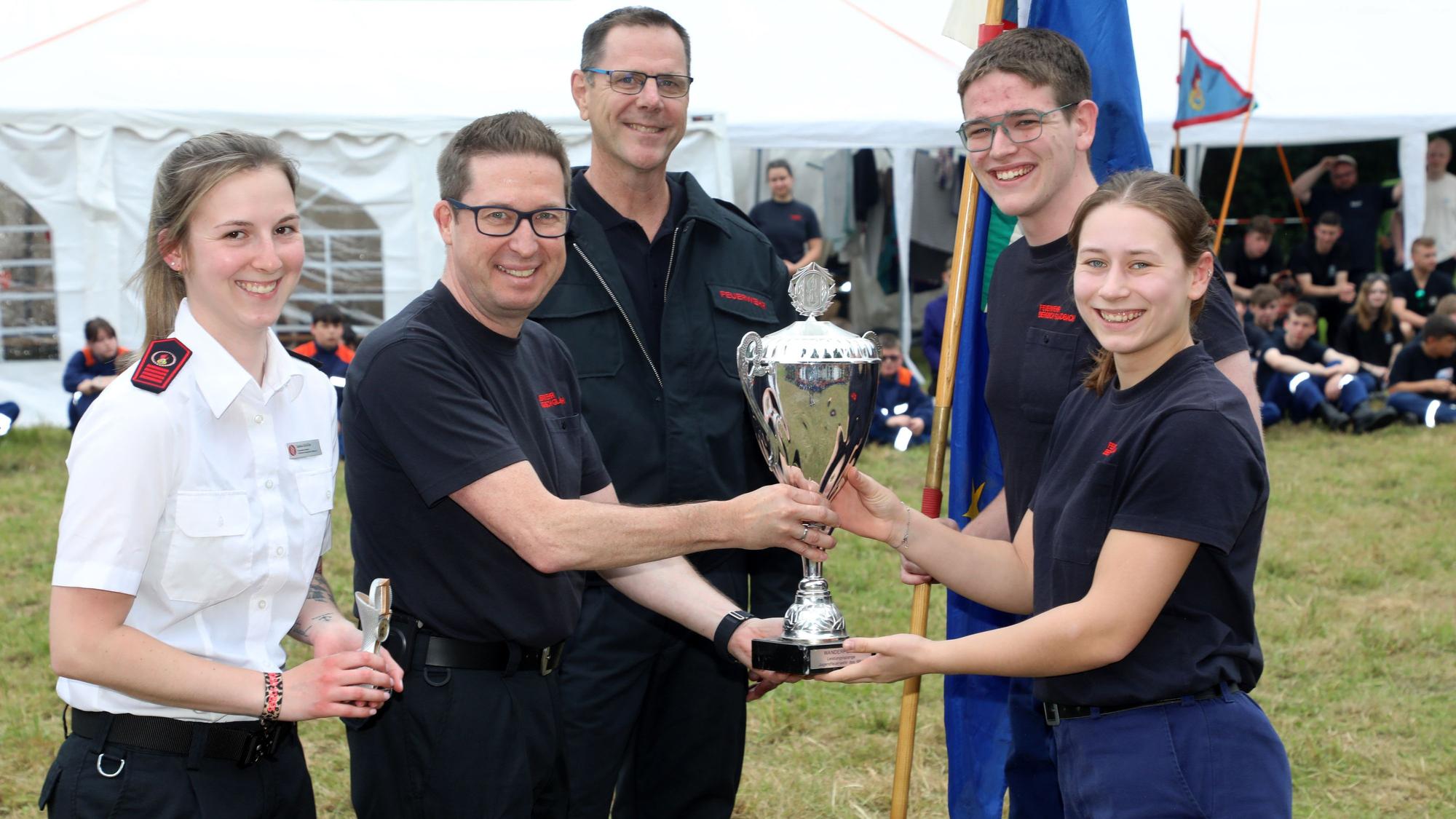 Frank Haag vom Kreisfeuerwehrverband überreicht den Pokal für die Sieger beim Leistungsspange-Wettbewerb zusammen mit Saskia Schüller (l.) und Feuerwehrkreisverbandschef Jörg Köhler an Marie Pütz von der Jugendfeuerwehr Bergisch Gladbach-Paffrath/Hand.
