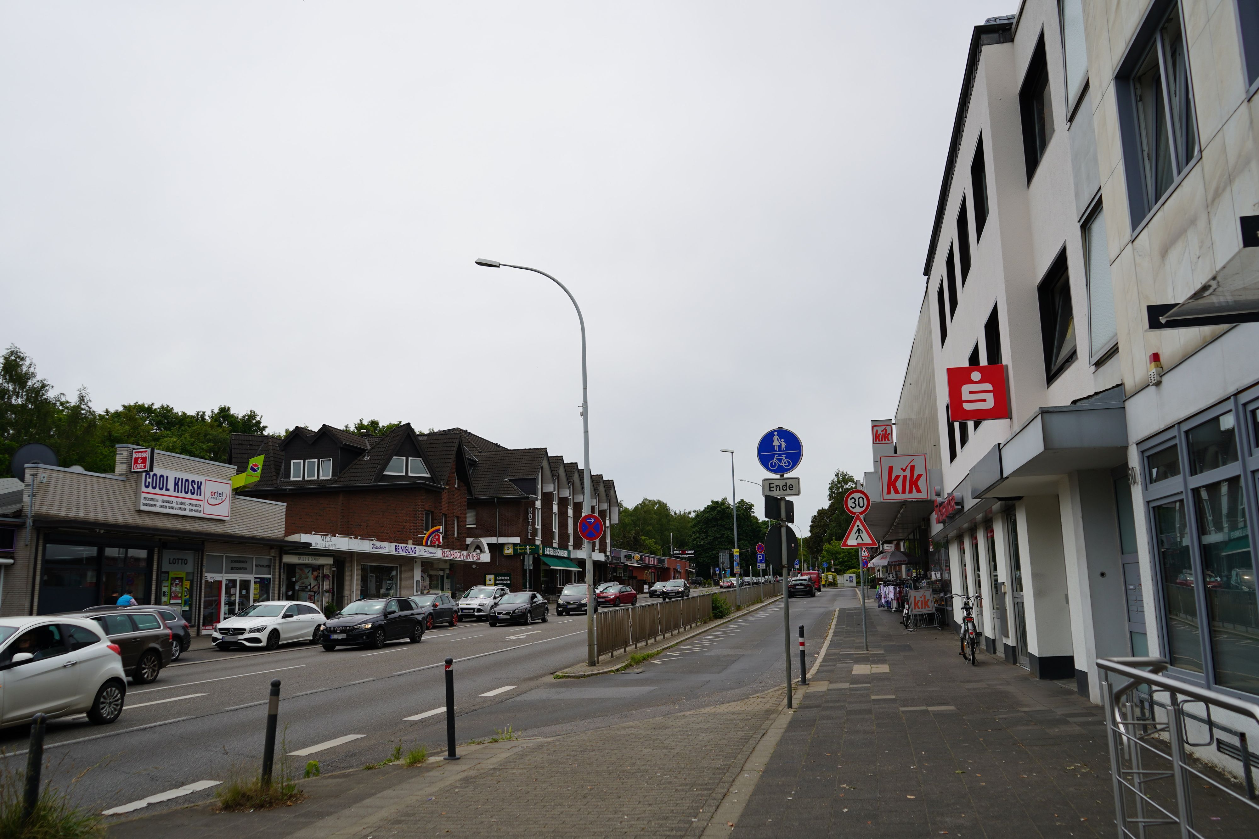 Das Bild zeigt die Dormagener Straße. Es sind viele Autos unterwegs, verschiedene Geschäfte haben sich dort angesiedelt.