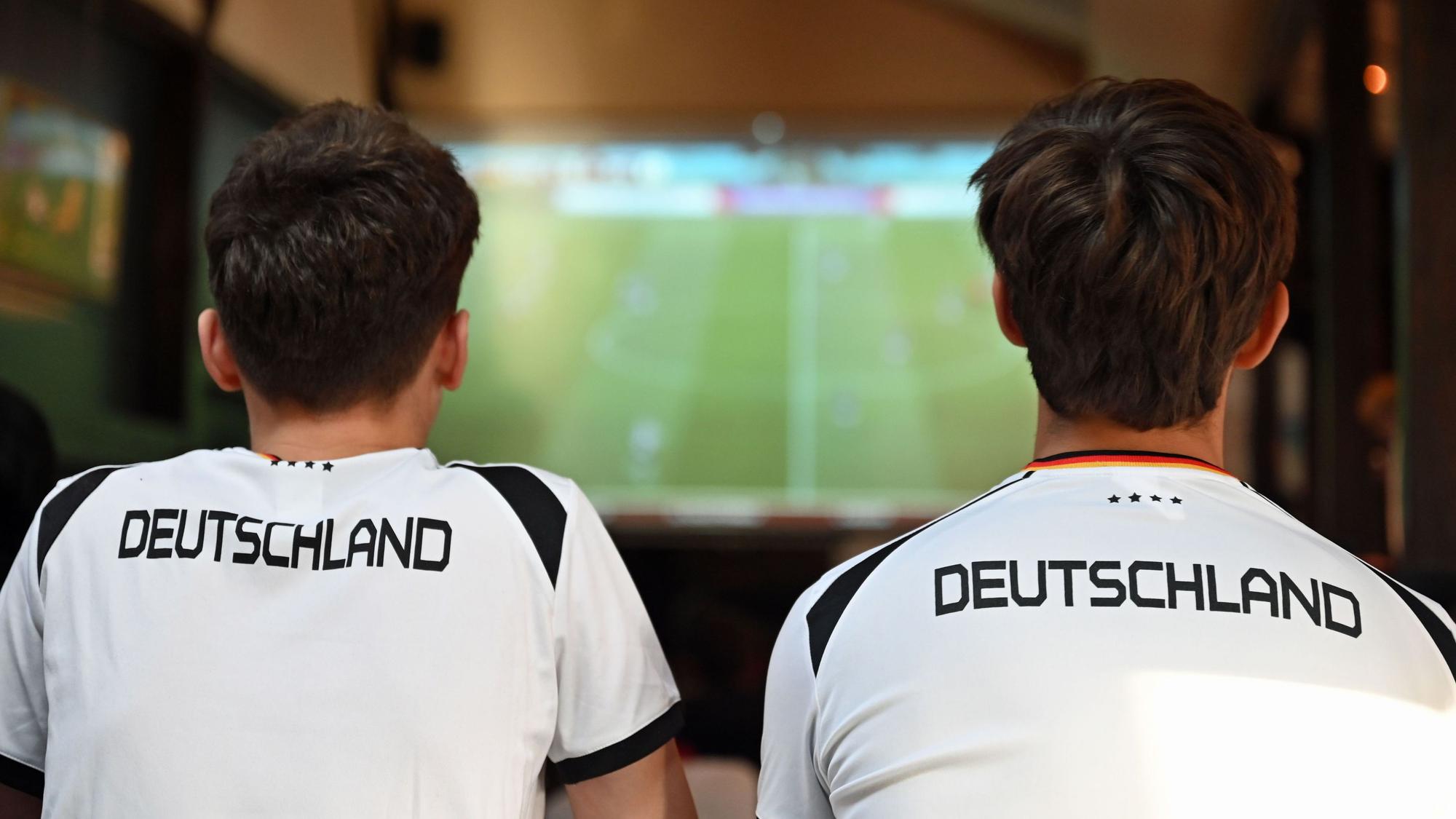 Zwei junge Männer sehen sich ein Fußballspiel in einer Kneipe an.