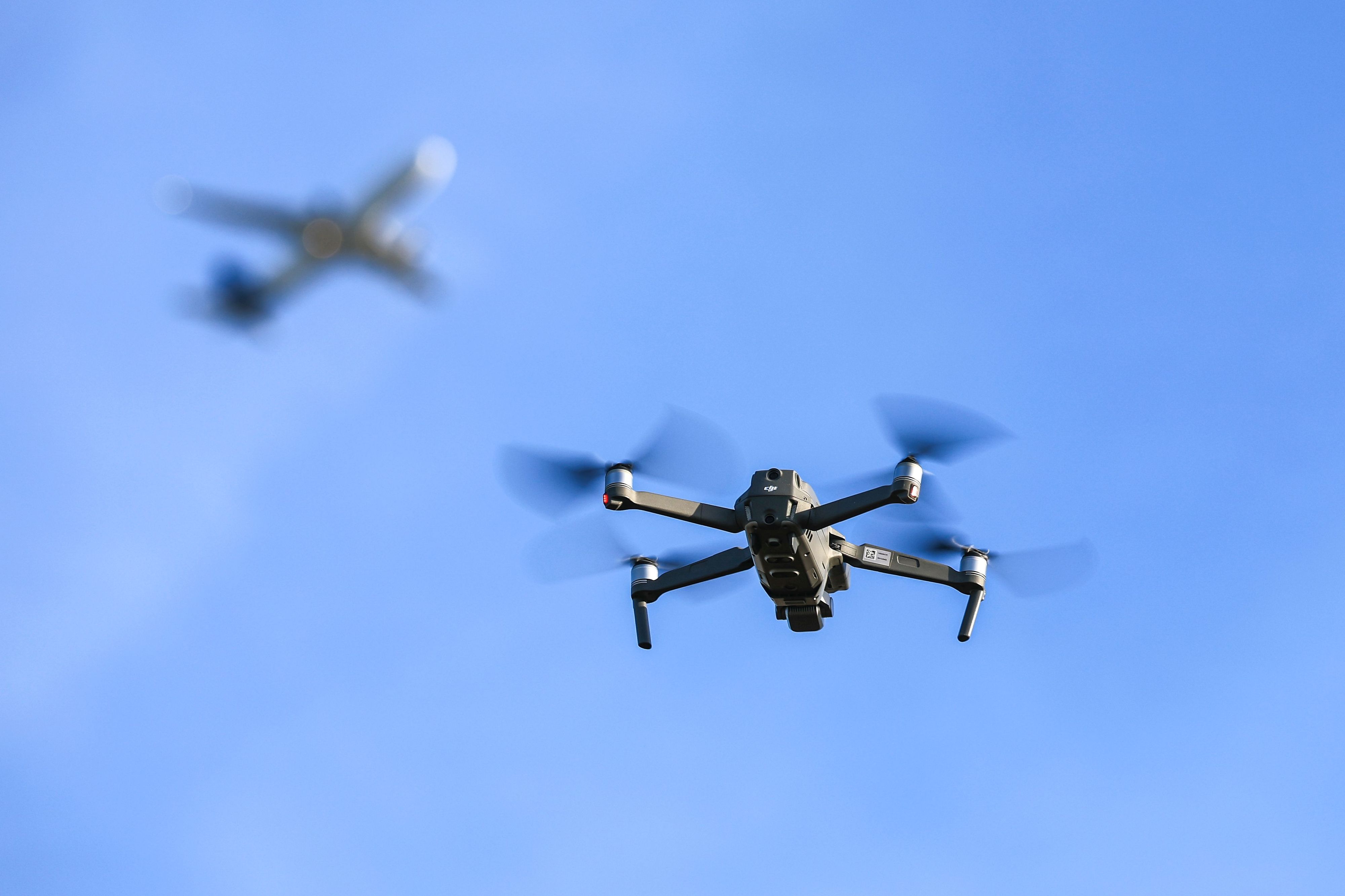 Eine Drohne fliegt vor einem startenden Flugzeug in der Nähe des Flughafens Leipzig/Halle. Immer wieder muss nach Drohnensichtungen an europäischen Flughäfen der Flugbetrieb temporär eingestellt werden.