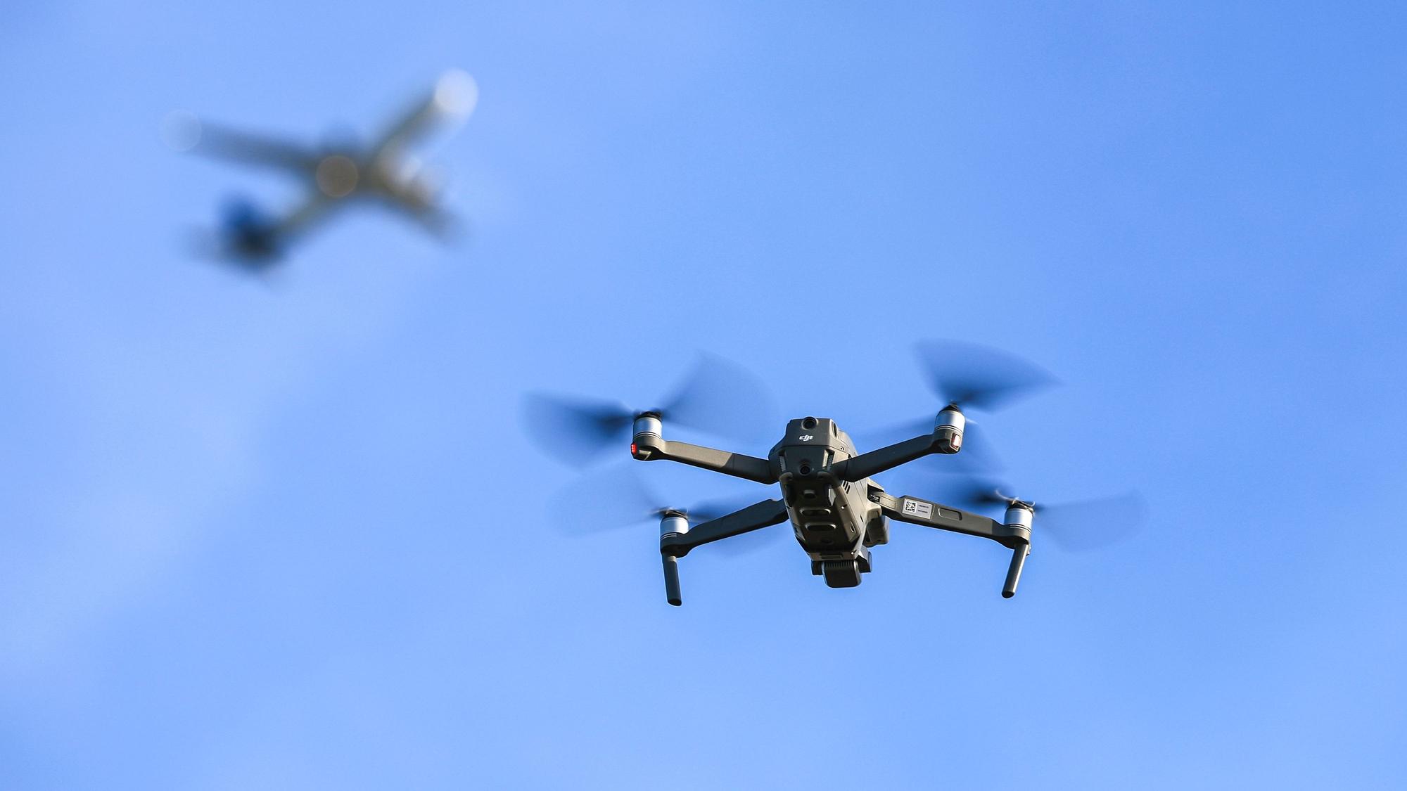 Eine Drohne fliegt vor einem startenden Flugzeug in der Nähe des Flughafens Leipzig/Halle. Immer wieder muss nach Drohnensichtungen an europäischen Flughäfen der Flugbetrieb temporär eingestellt werden.