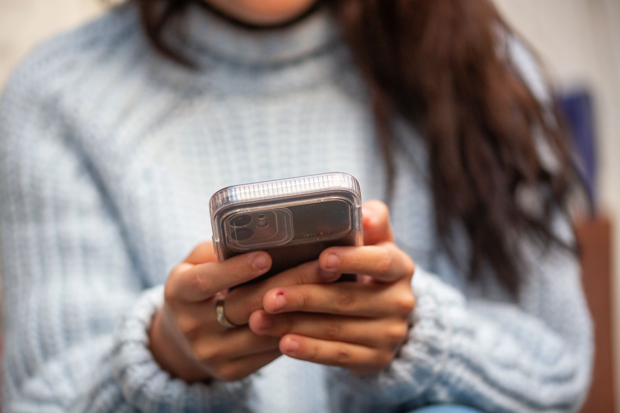 Eine junge Frau hält ein Smartphone in den Händen