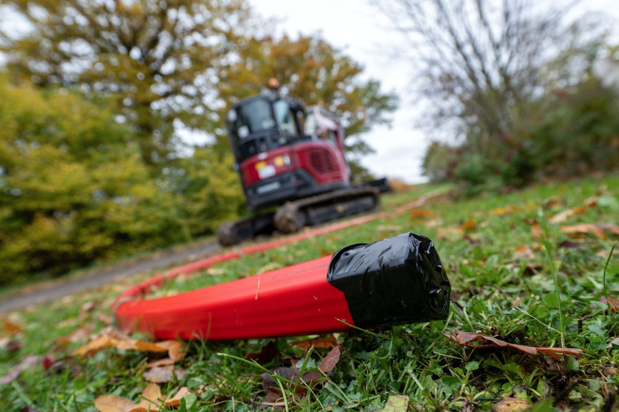 Ein Schutzrohr für Glasfaserkabel liegt vor einem Bagger