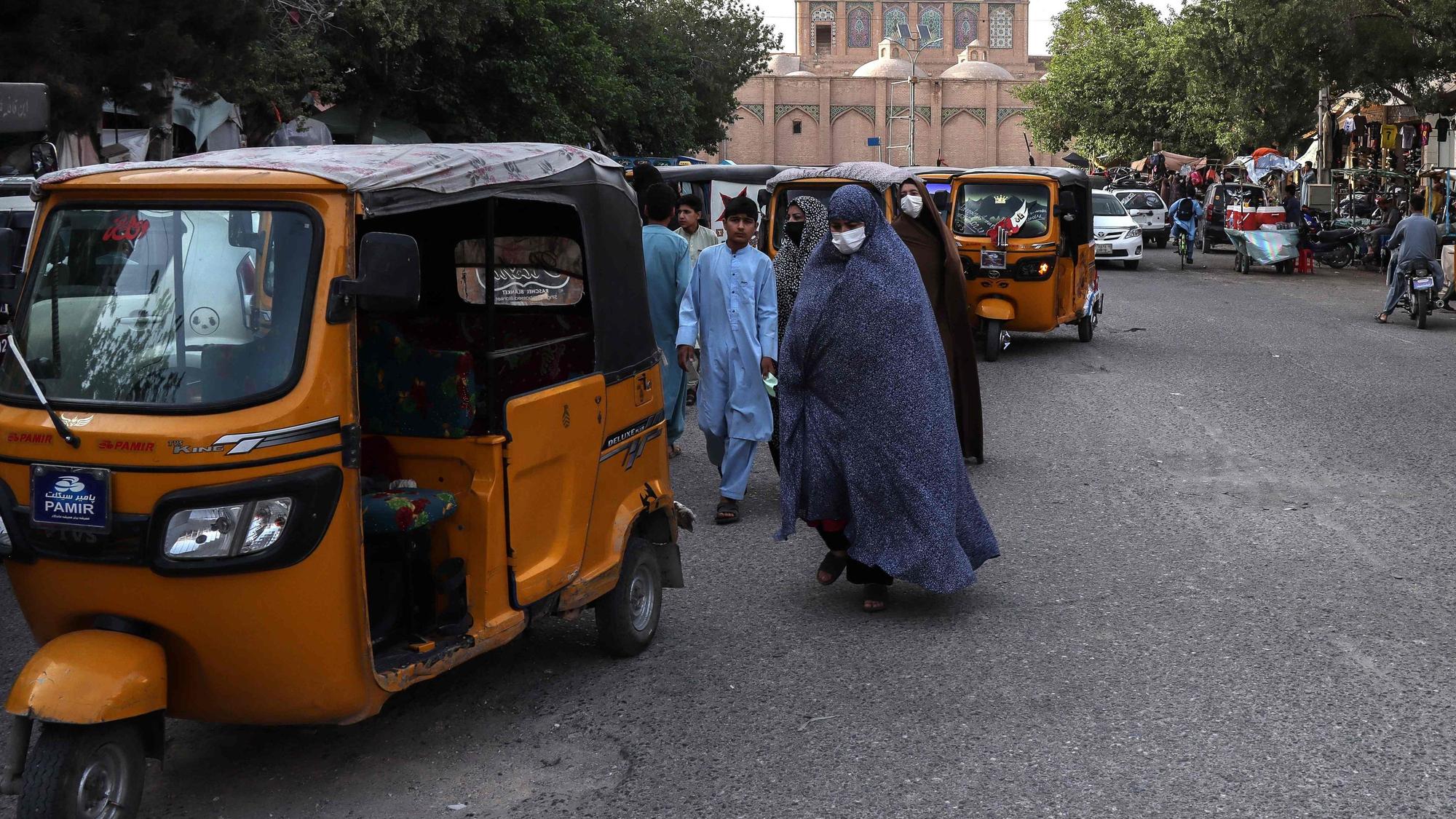 Afghanische Frauen in Tschadoren gehen am 8. Juni 2026 nahe der Großen Moschee in Herat eine Straße entlang.