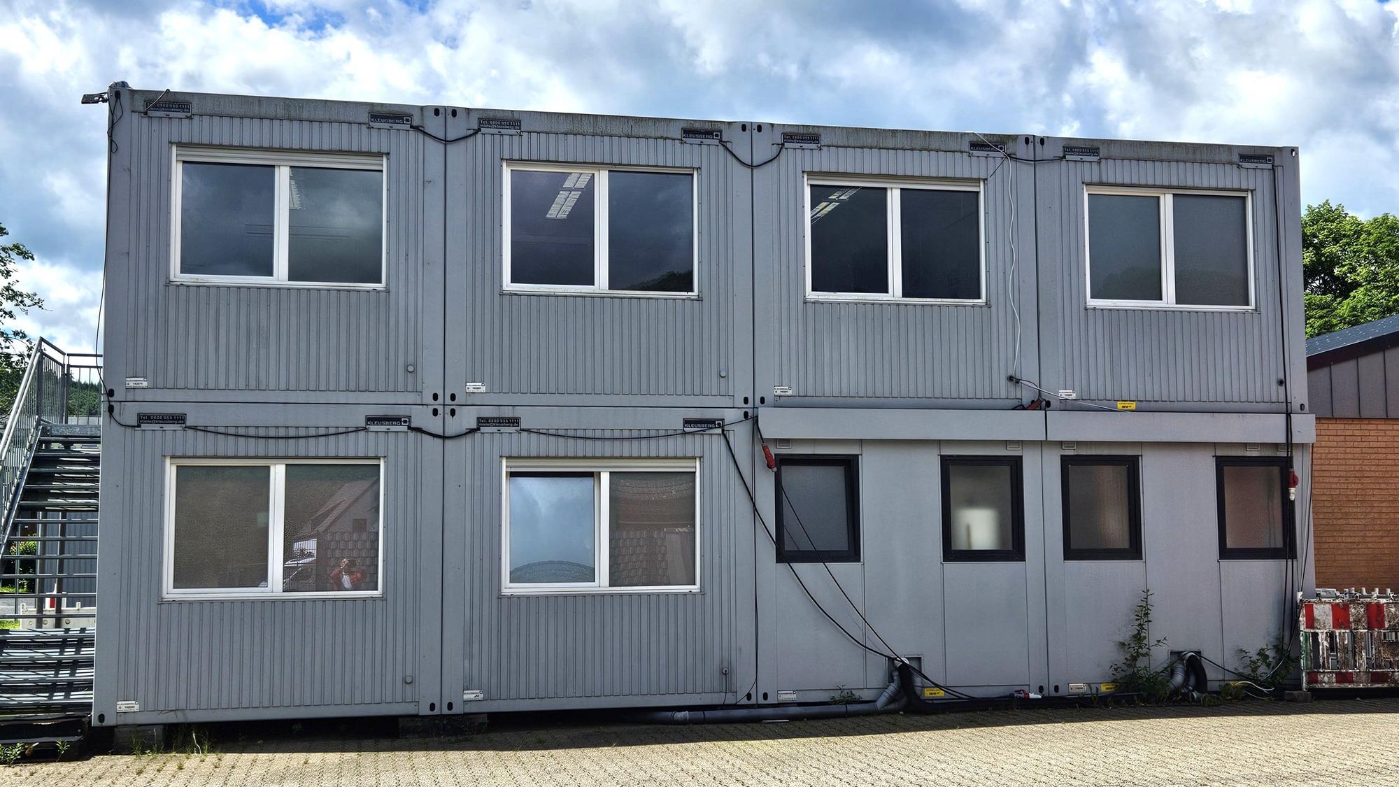 In zwei Reihen sind acht Büro-Container übereinander gestapelt.