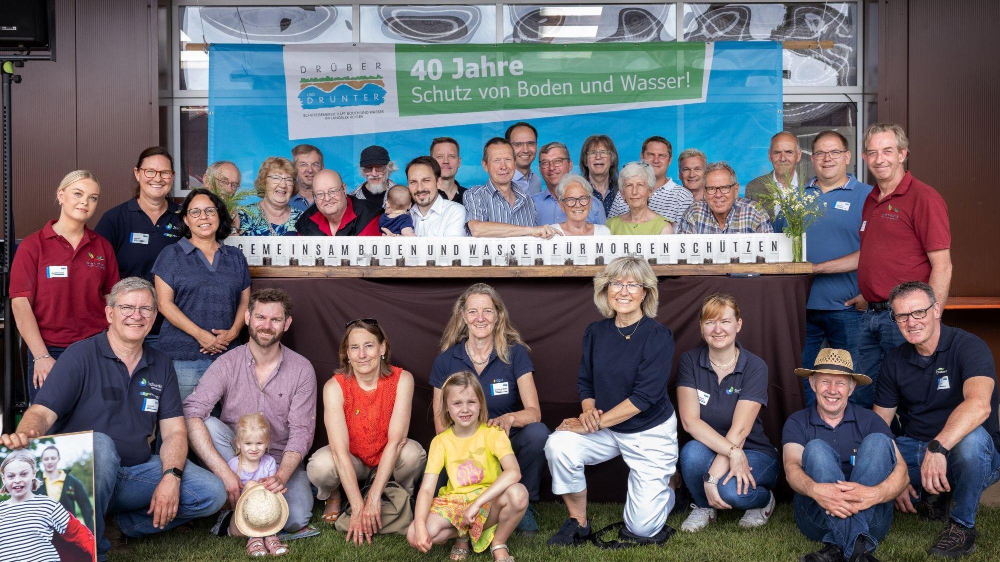 Viel Menschen stehen um einen Stand herum, auf dem der Slogan steht: Gemeinsam Boden und Wasser für morgen schützen.