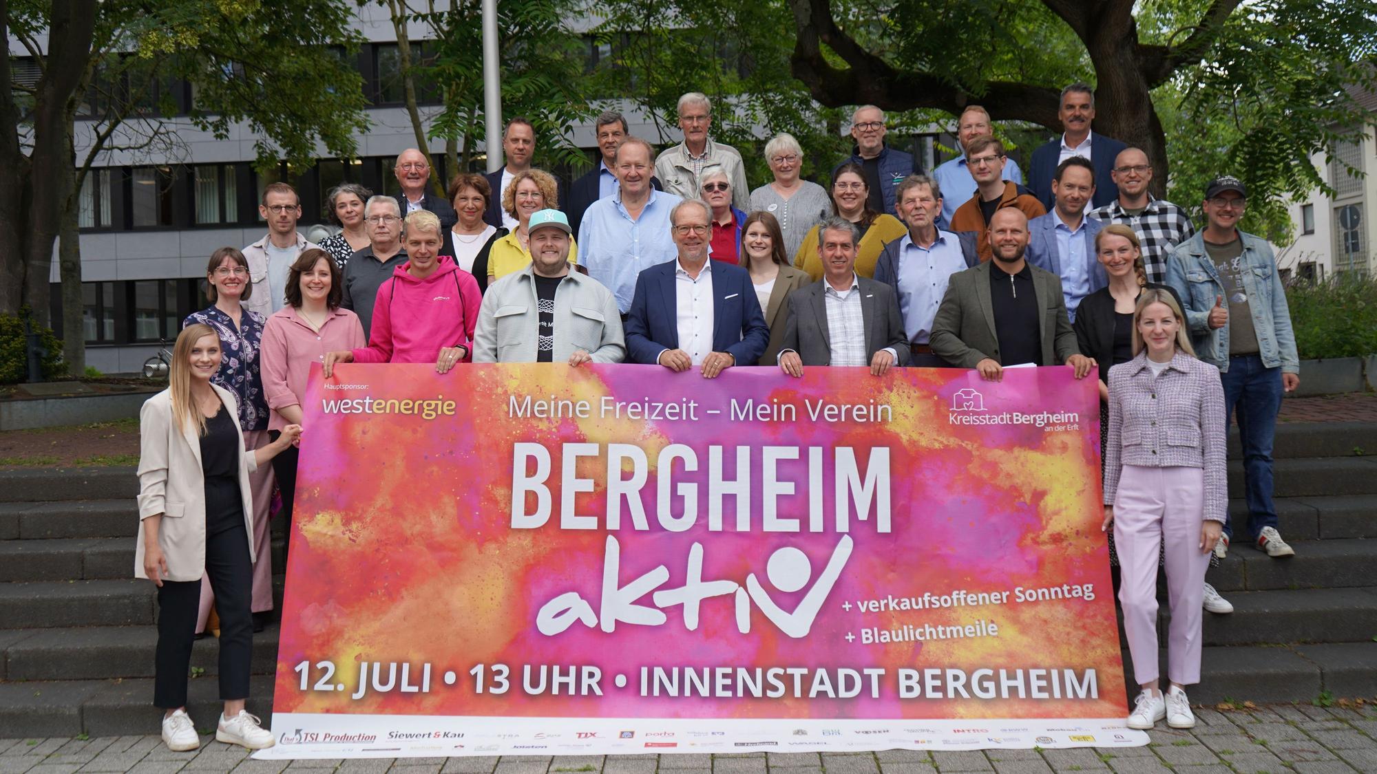 Das Bild zeigt ein Banner mit der Aufschrift „Bergheim aktiv“. Vertreter der Verwaltung sowie der vielen Vereine und Sponsoren haben sich zu einem Gruppenbild versammelt.