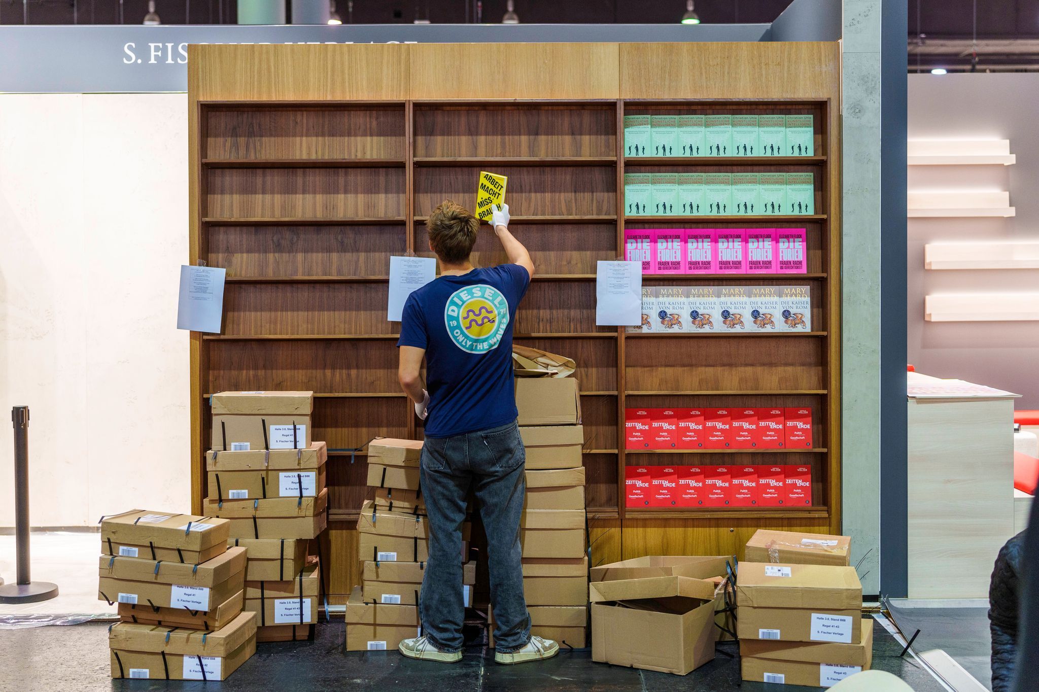 Ein junger Mann räumt Bücher in ein Regal ein