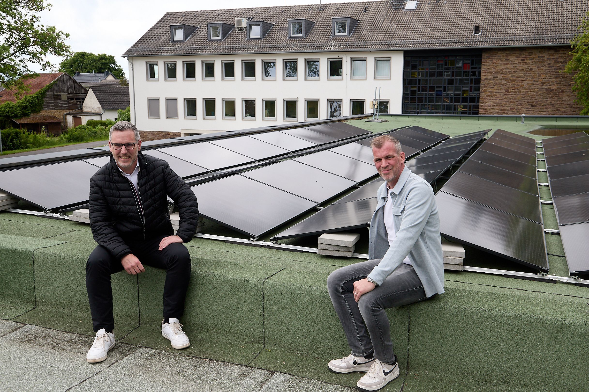 Norbert Crump und Jens Berbuir sitzen an der Photovoltaikanlage auf dem Dach des Feuerwehrgerätehauses.