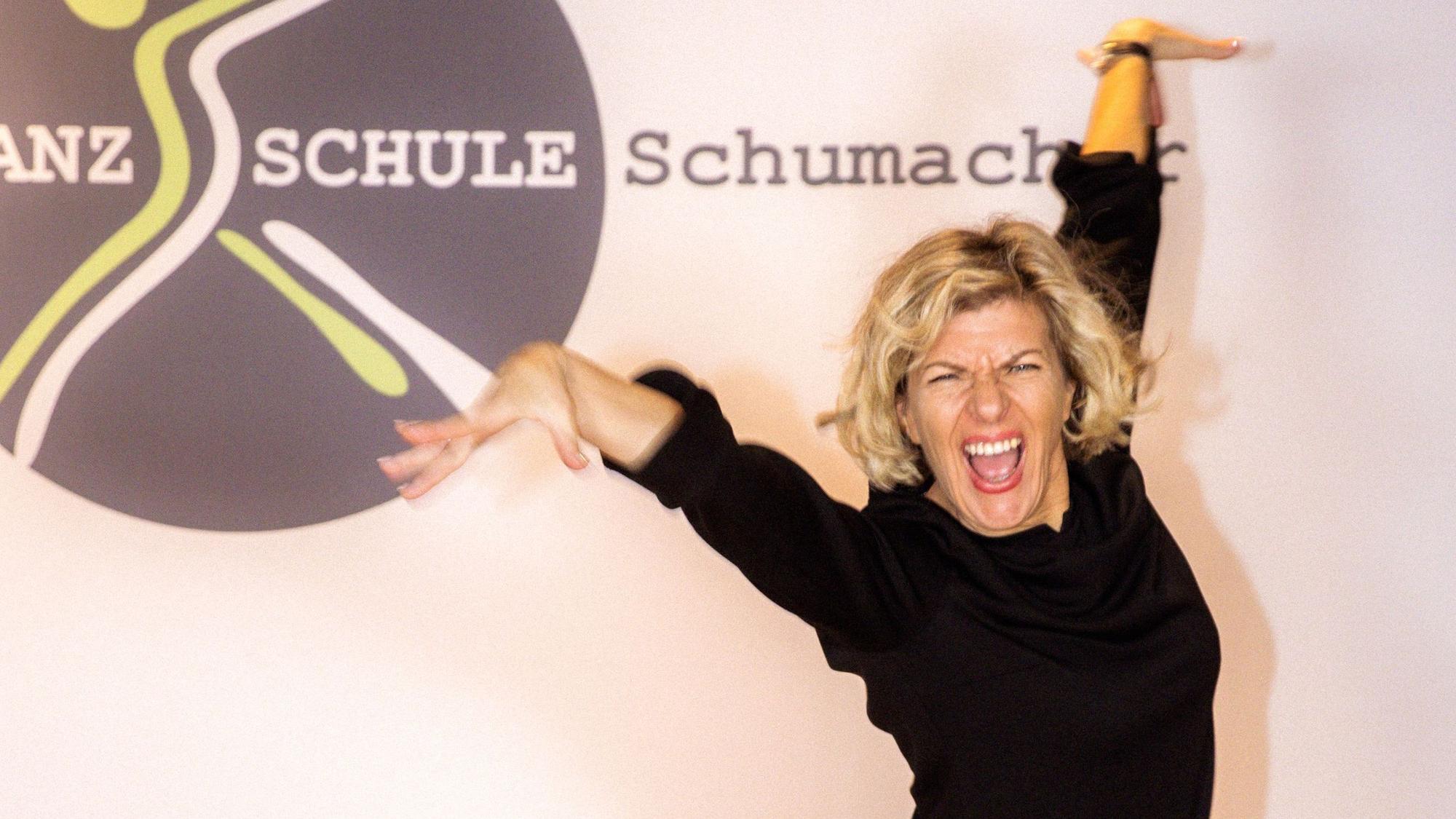 Eine Tanzlehrerin posiert vor dem Logo ihrer Tanzschule.