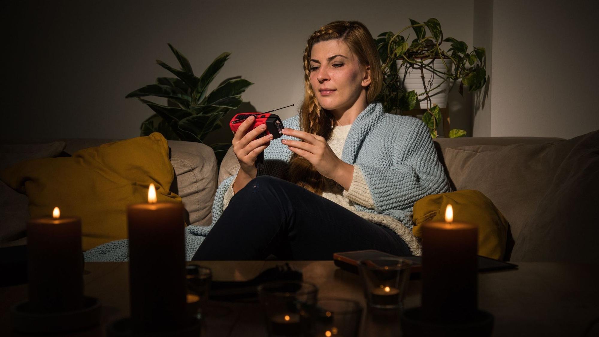 Eine Frau mit Kerzen während eines Stromausfalls auf dem Sofa