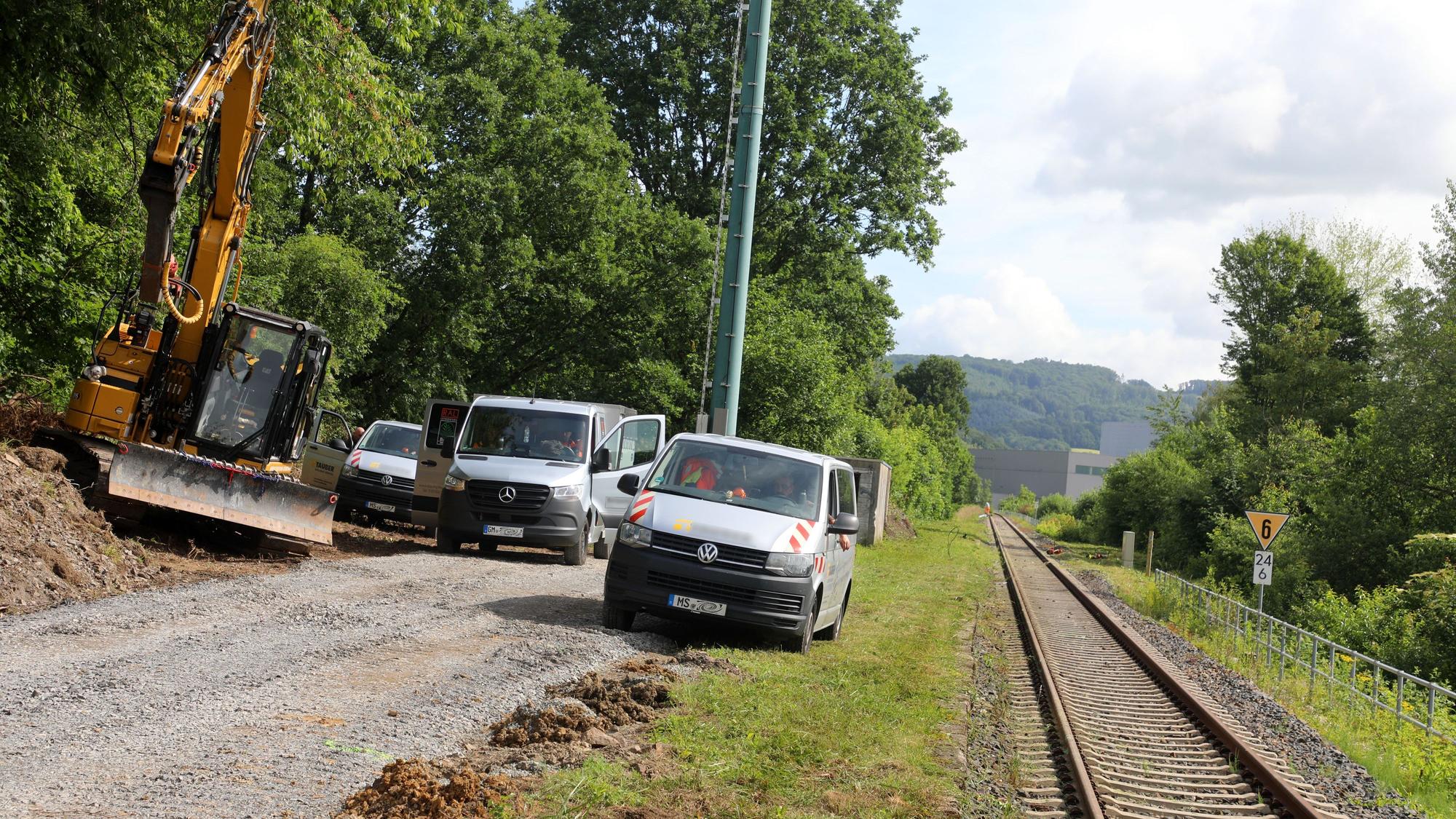 Baufahrzeuge und ein Bagger stehen neben einem frisch geschotterten Weg an der Regionalbahnstrecke 25 in Overath-Vilkerath.