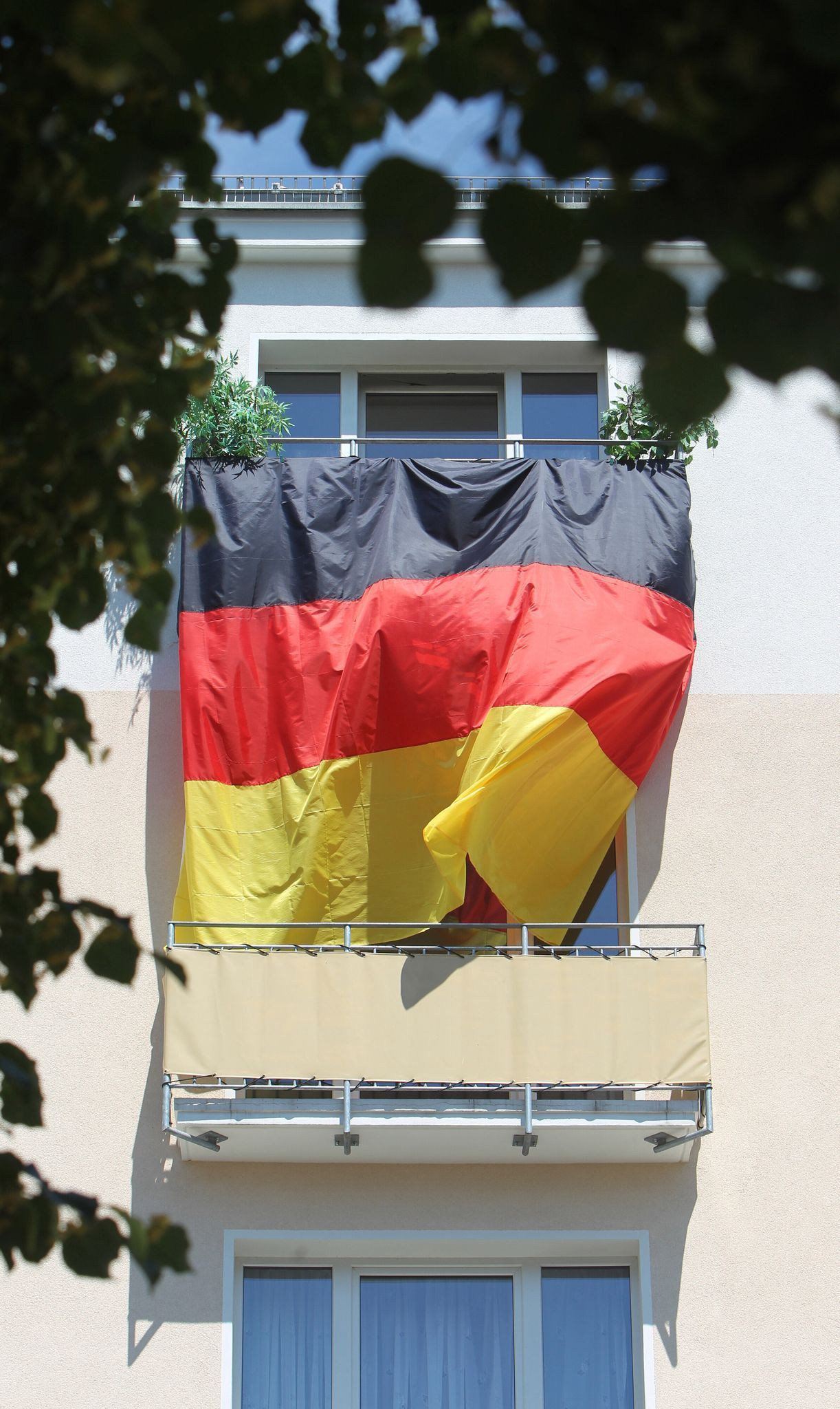 Eine Deutschlandflagge hängt von Balkon zu Balkon