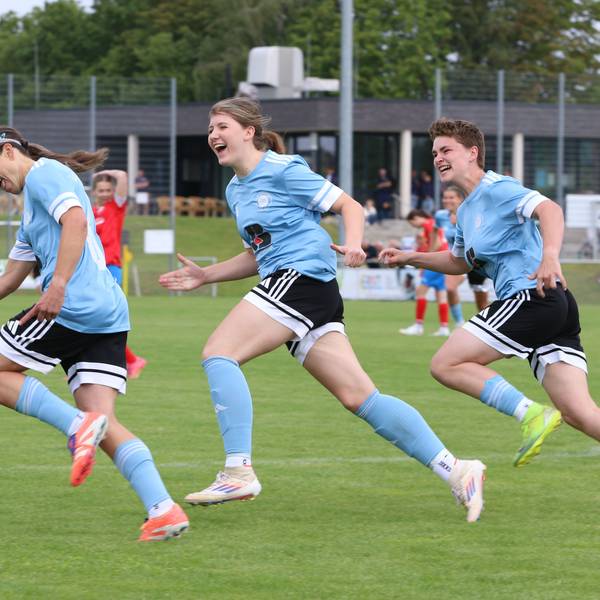 Drei Fußballerinnen freuen sich über ein Tor.