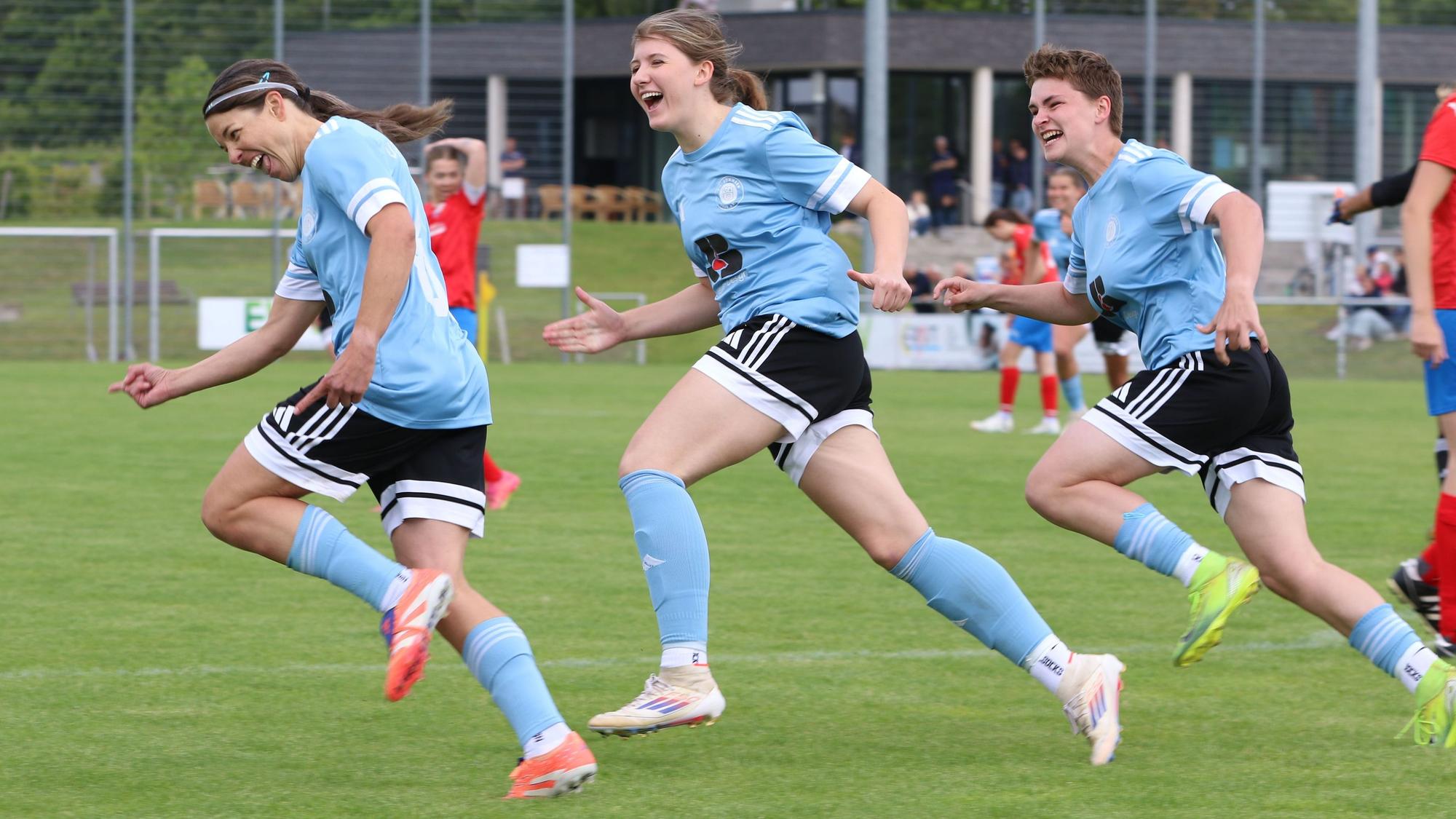 Drei Fußballerinnen freuen sich über ein Tor.