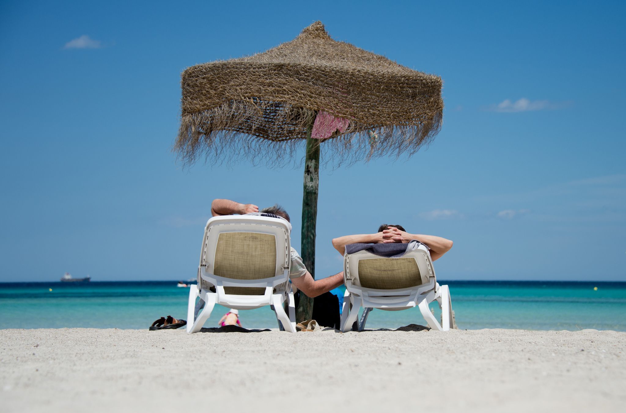 Touristen liegen am Strand unter einem Sonnenschirm