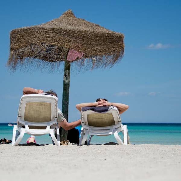 Touristen liegen am Strand unter einem Sonnenschirm