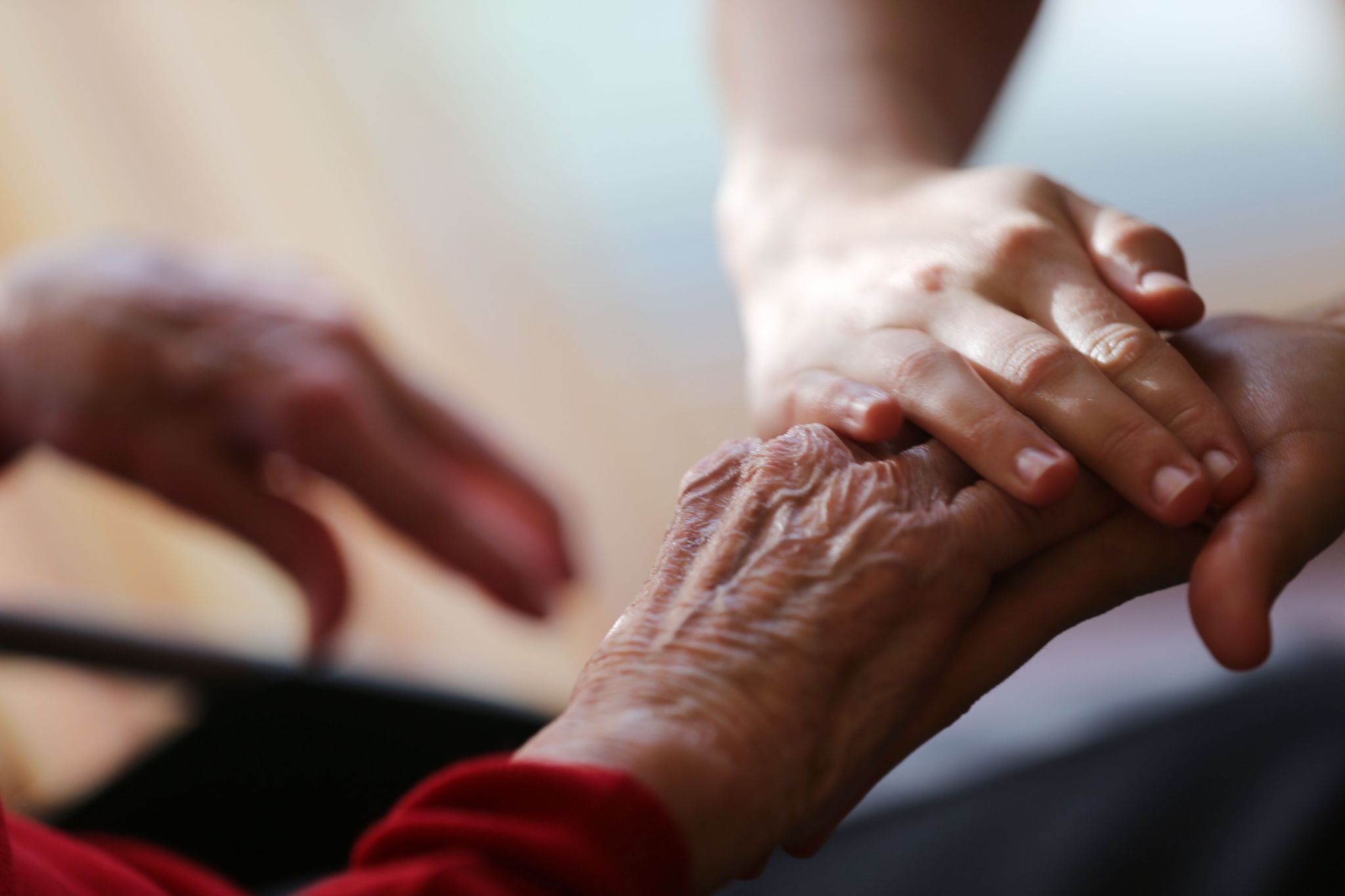 Eine Pflegekraft streicht einer Seniorin über die Hand