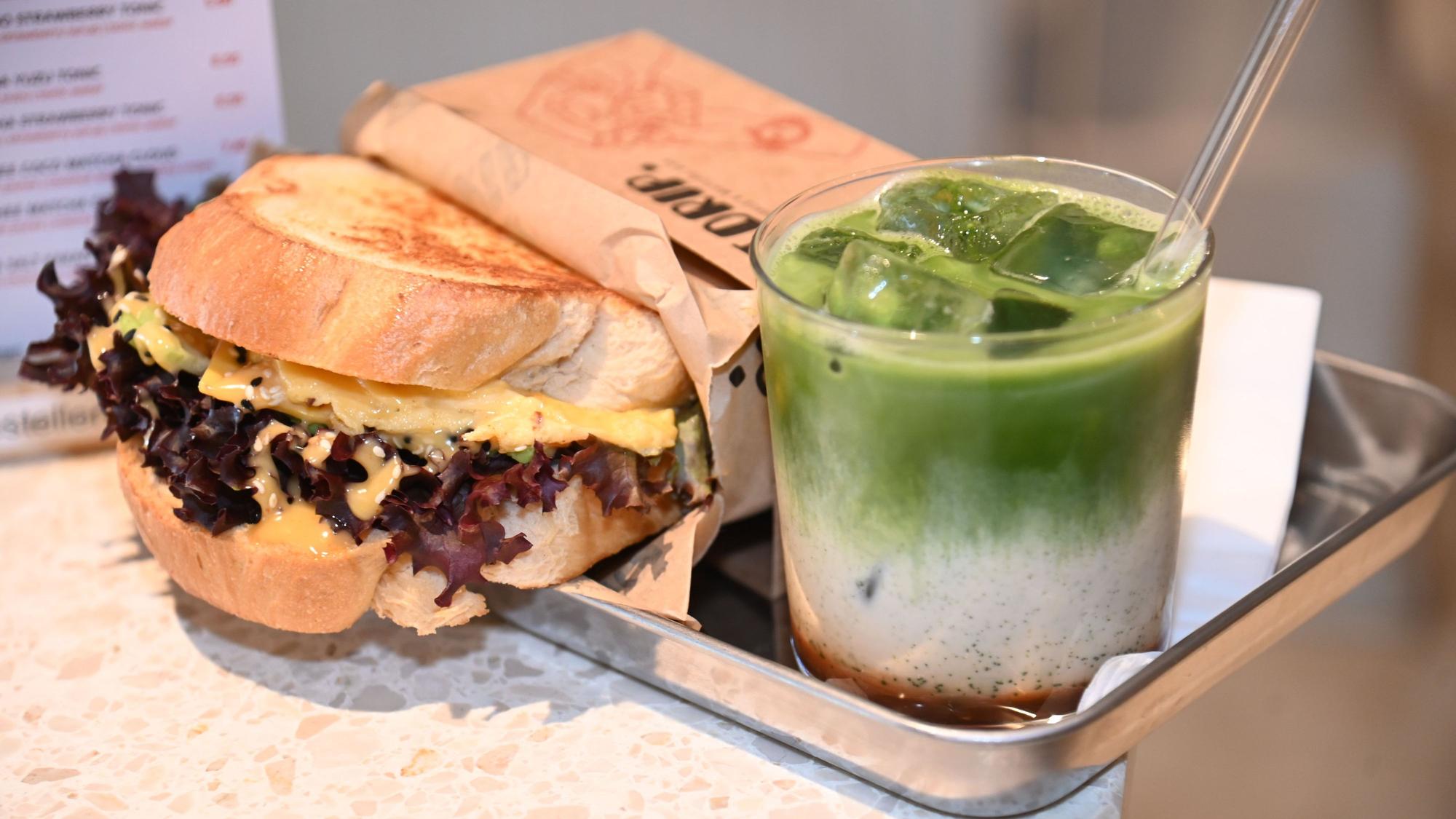 Ein Sandwich und ein Iced-Matcha-Latte, serviert auf einem silbernen, eckigen Tablett
