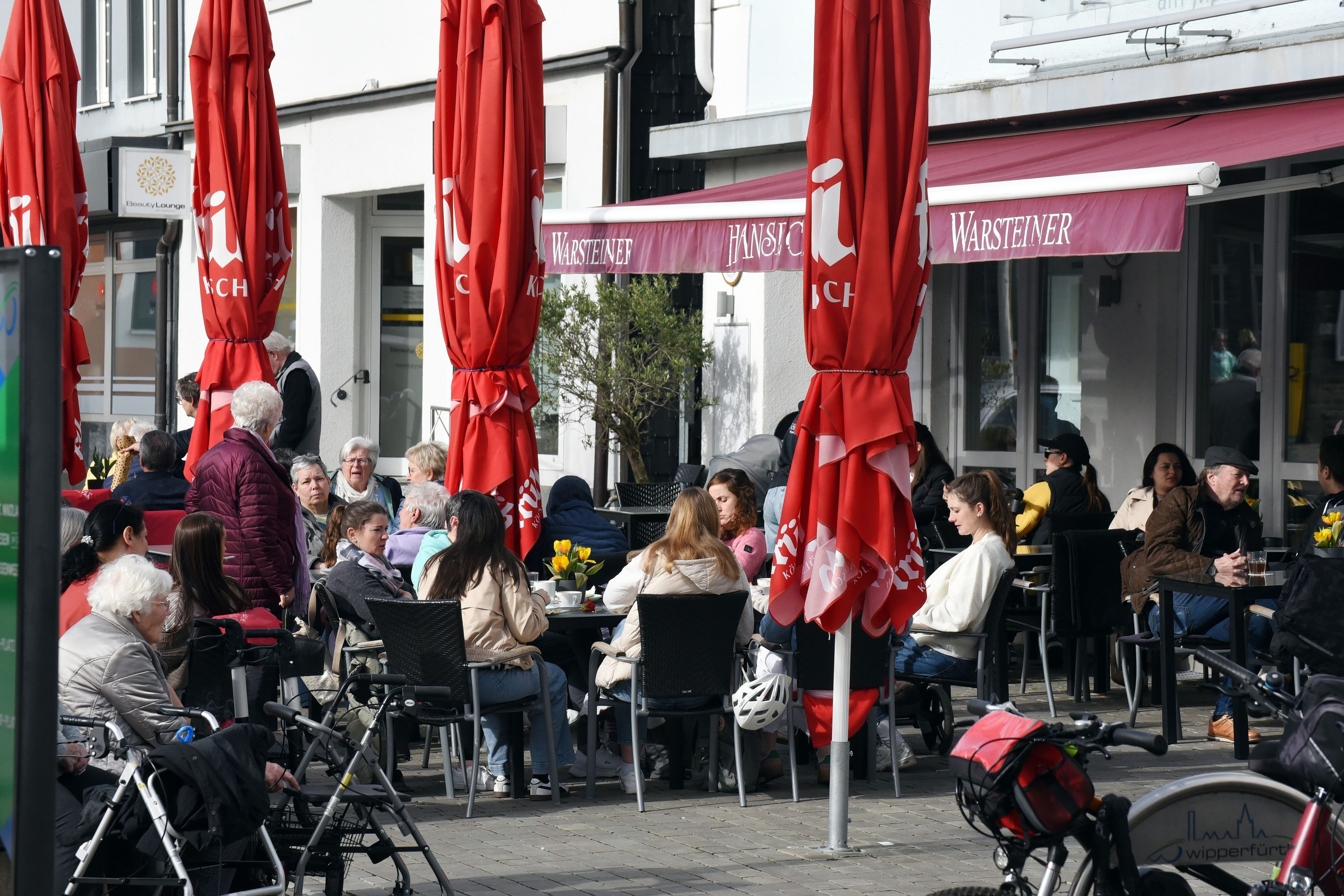 Das Foto zeigt Gäste an Tischen vor einer Gaststätte am Wipperfürther Marktplatz.