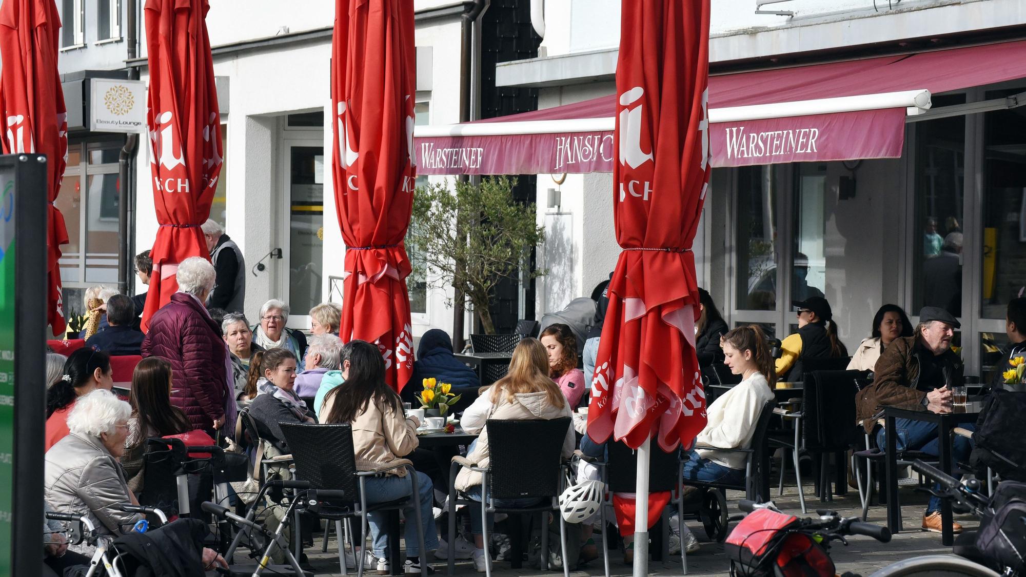 Das Foto zeigt Gäste an Tischen vor einer Gaststätte am Wipperfürther Marktplatz.