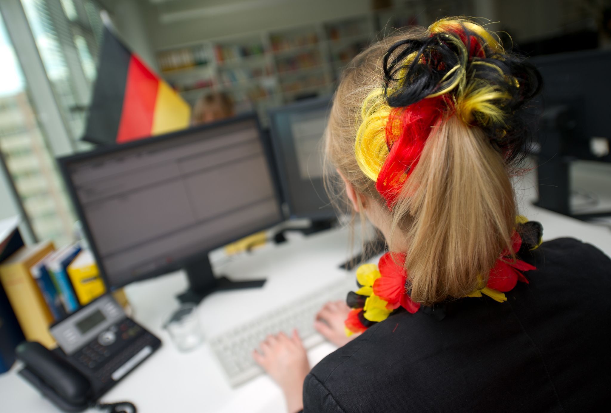 Eine Frau sitzt mit WM-Deko vor einem Computer