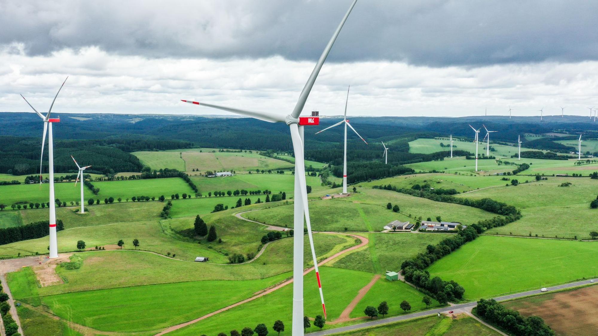 Mehrere Windräder stehen in der Eifellandschaft.