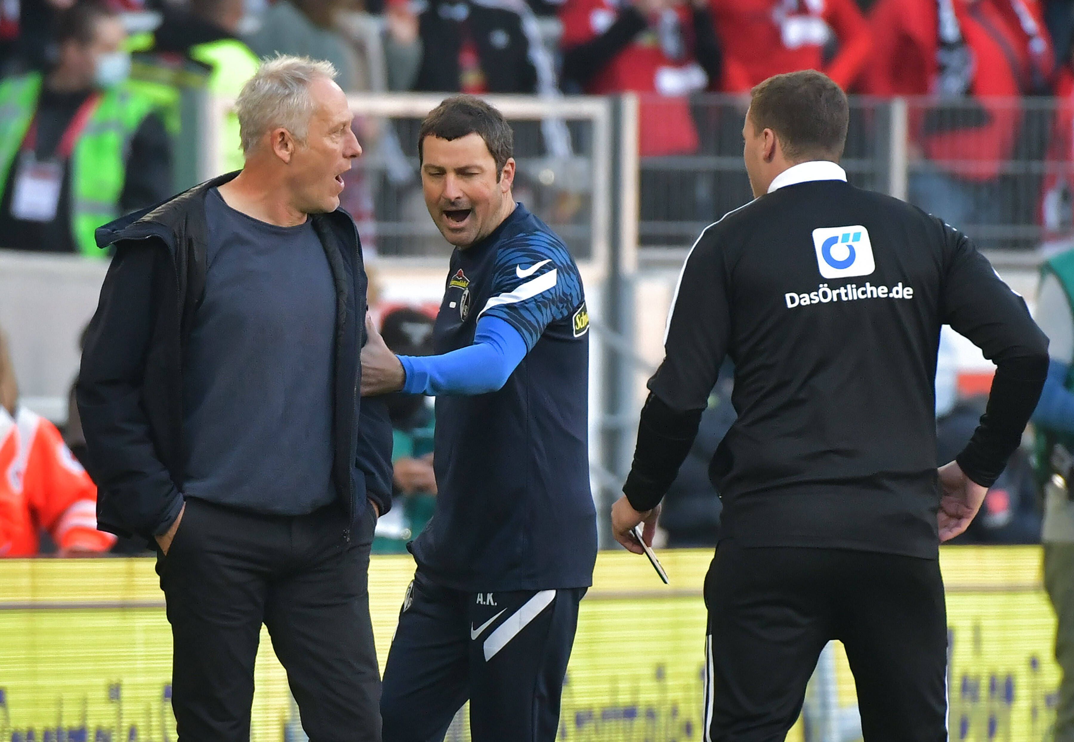 Der wütende Christian Streich wird von seinem Co-Trainer zurückgehalten.